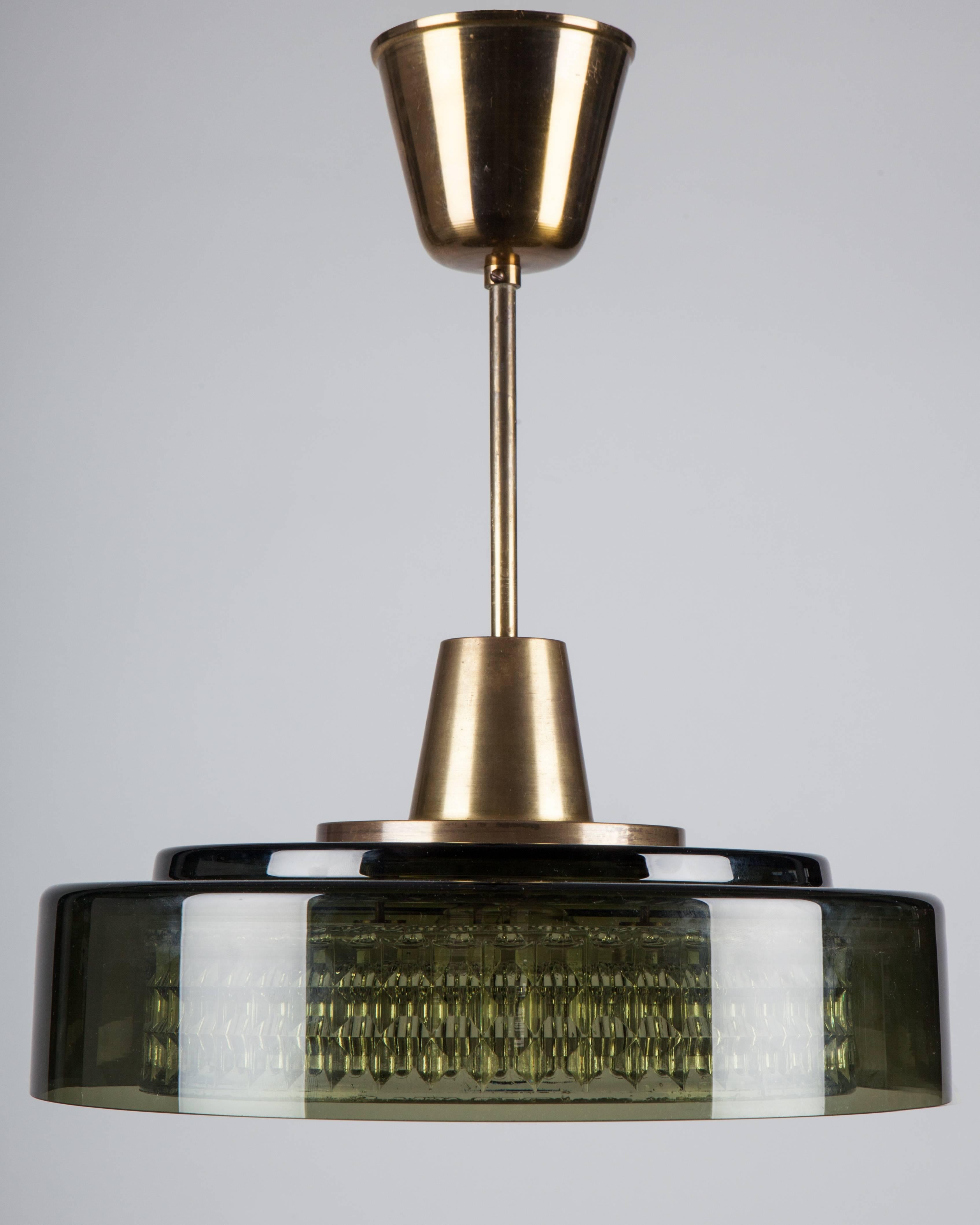 AHL3991.
A vintage olive and clear glass pendant suspended on brass fittings in their original patina. This mid century modern fixture was designed by Carl Fagerlund for the Swedish glassmaker Orrefors. Due to the antique nature of this fixture,