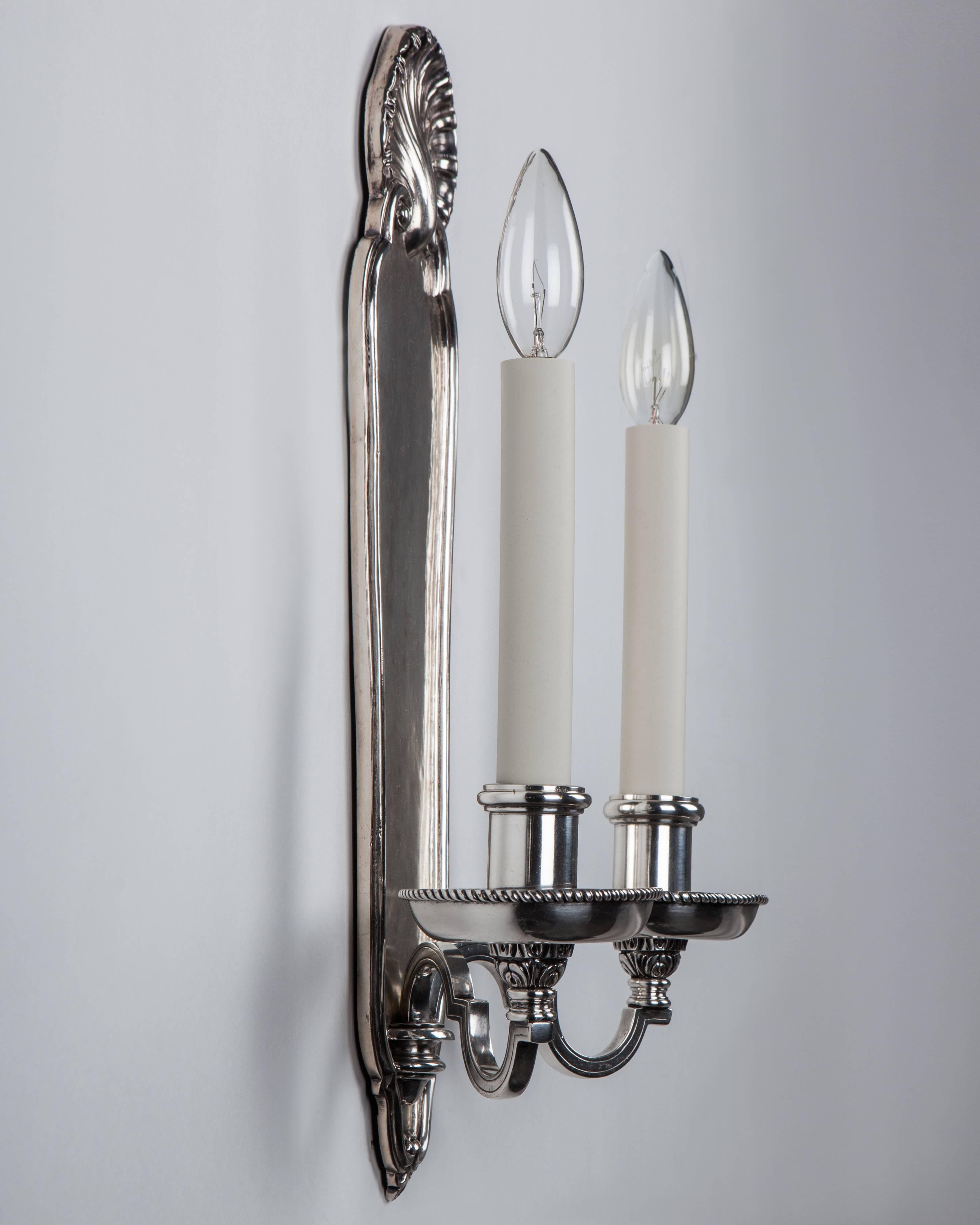 AIS2965.
A pair of antique silver plate double-light sconces with rope edge-detailed waxpans and tall shell-topped backplates. Attributed to the New York maker E. F. Caldwell Co.

Dimensions:
Overall: 18