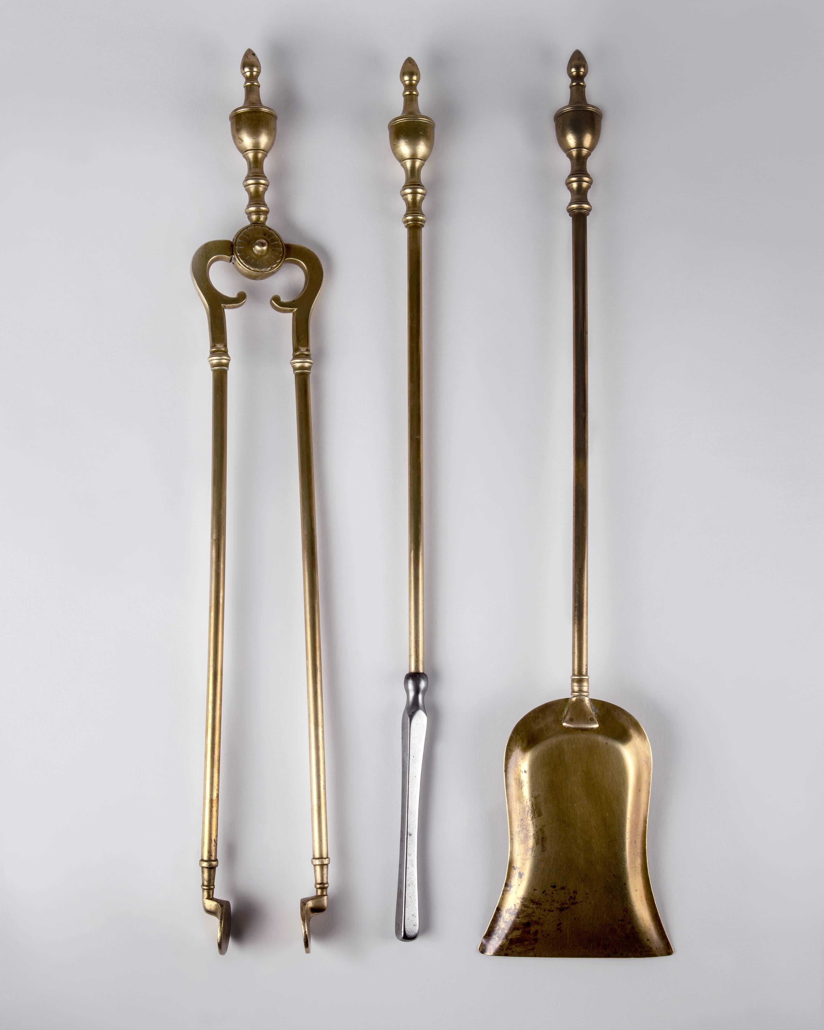 An antique fireplace tool set with a poker, a shovel, tongs and a caddy in its original aged brass finish, circa 1930.

Dimensions:
Overall: 27-1/4