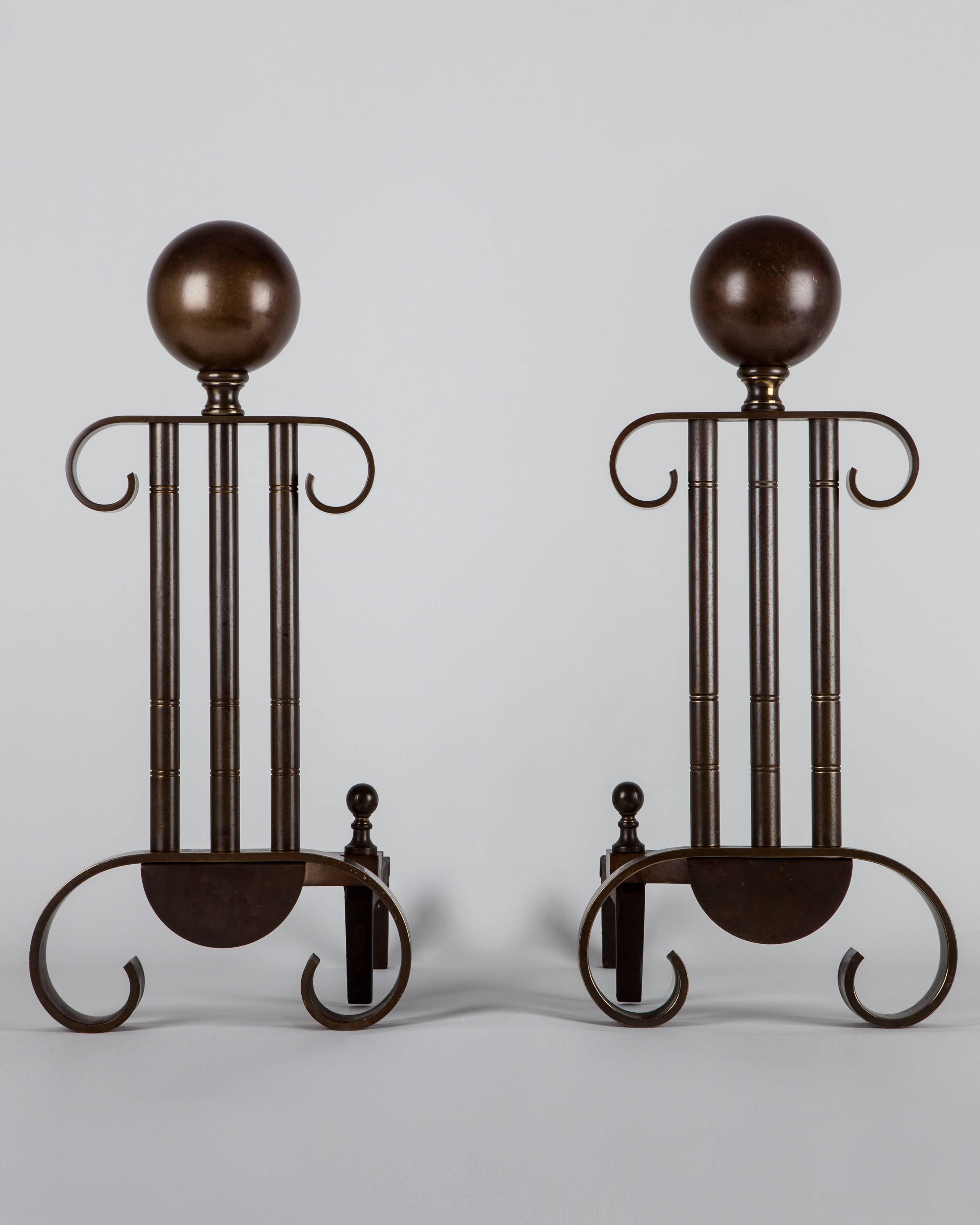 AFP0520
A pair of vintage andirons in the stylized neoclassical form of fluted ionic columns, surmounted by large spheres. In their original age-darkened brass finish.

Dimensions:
Overall: 20-1/2