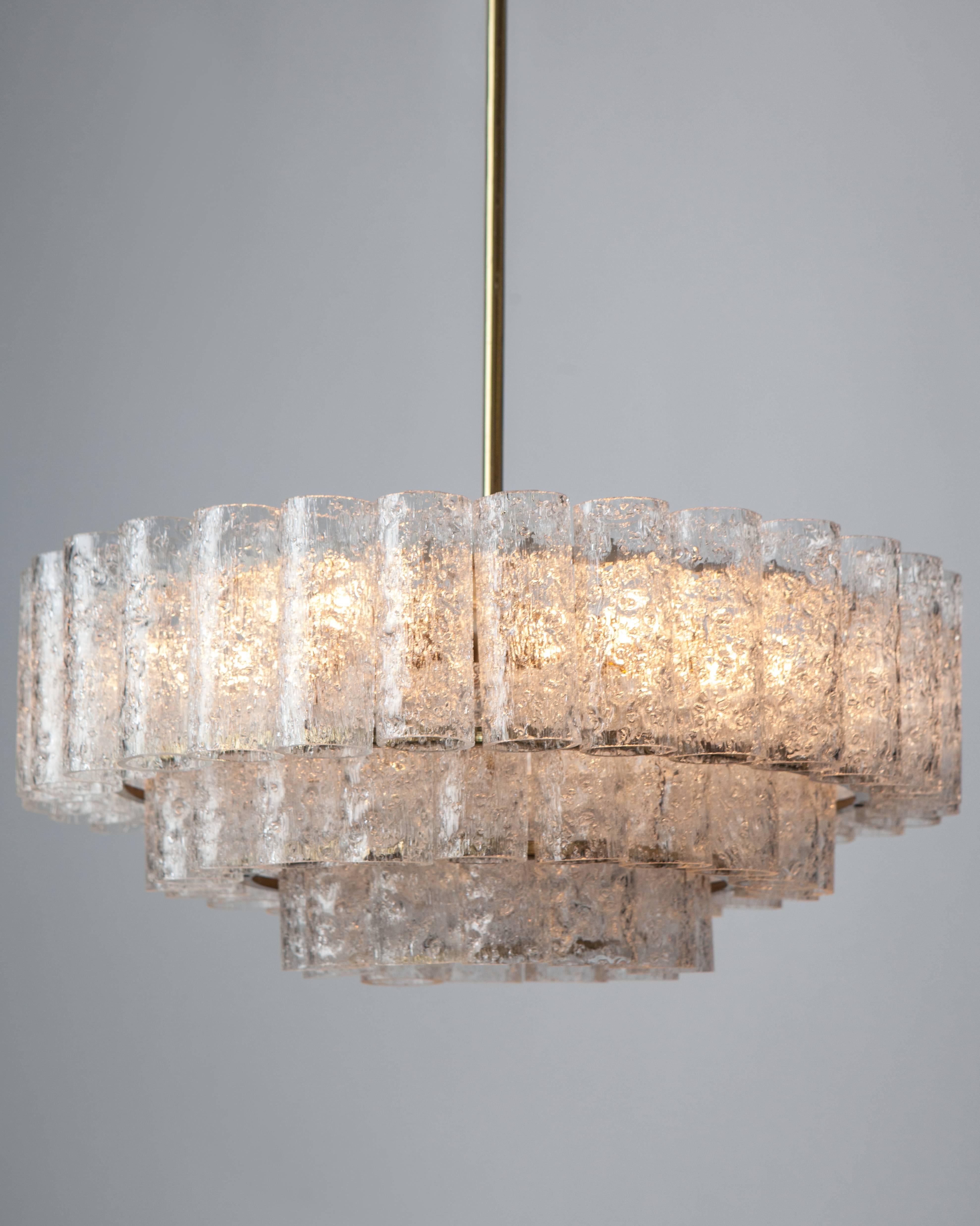 AHL4005.
A vintage chandelier having an old bright brass finished frame with textured clear glass shades in three descending rings. Signed by the German maker Doria. Due to the antique nature of this fixture, there may be some nicks or