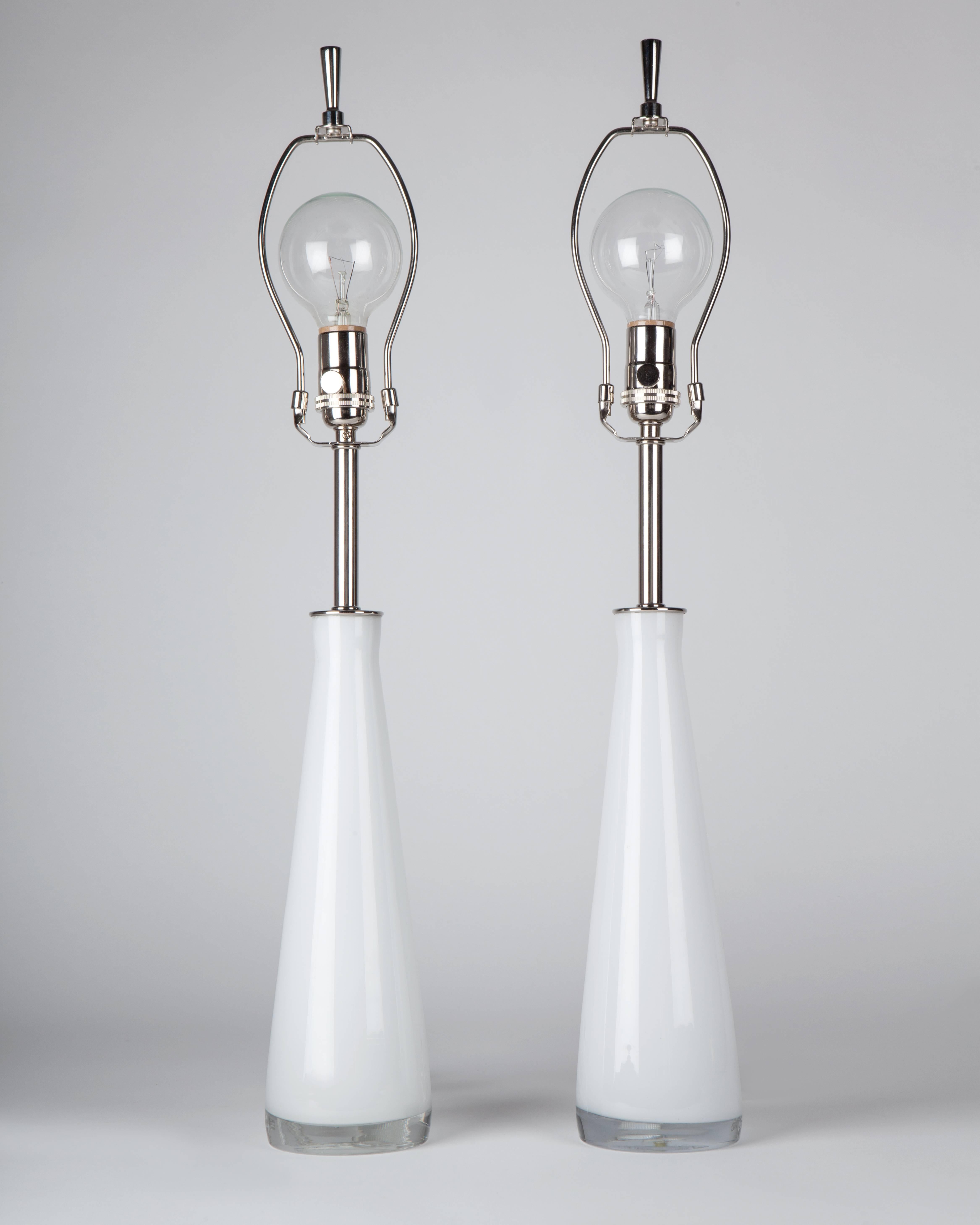 ATL1942.
A pair of white cased glass lamps with nickel fittings by the Swedish maker Falkenbergs Belysning. Due to the antique nature of this fixture, there may be some nicks or imperfections in the glass.

Dimensions:
Overall: 27-1/4