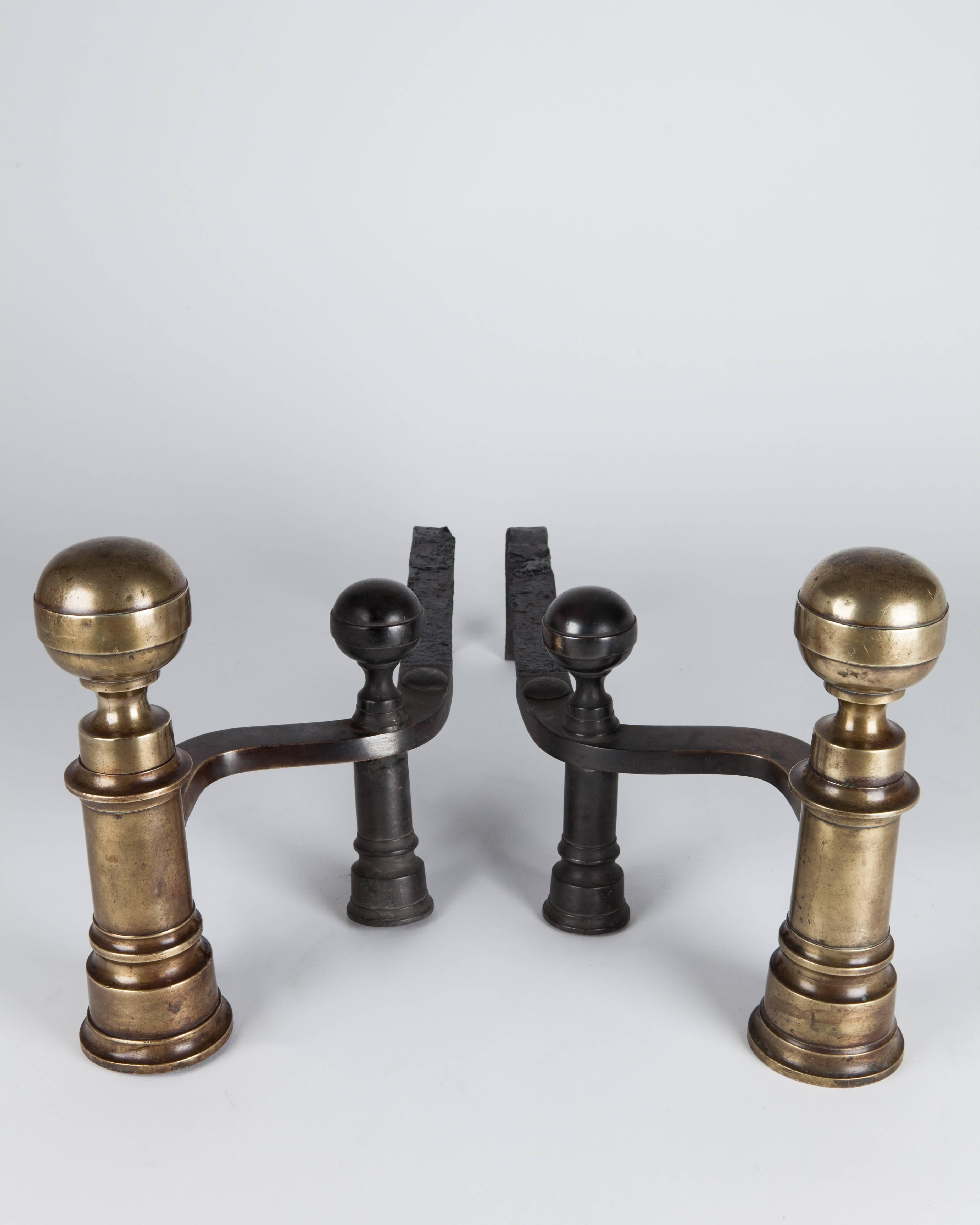 AFP0561
A pair of andirons in their original aged brass and blackened iron finish, after a pattern by the Boston maker William Hunneman having tapered bodies topped with ball finials. A related pair is shown in Donald Fennimore's book 