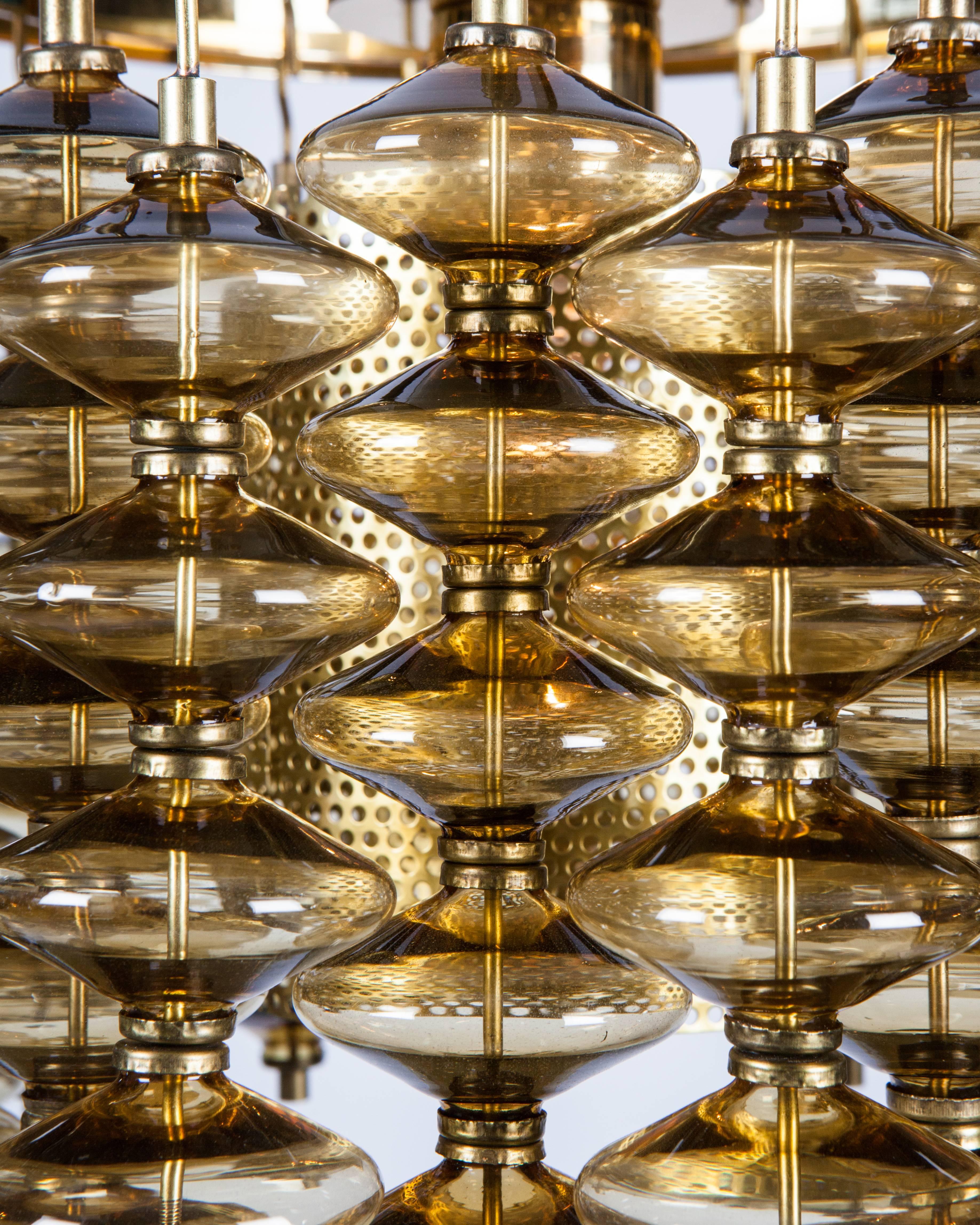 AHL4031

A circular chandelier with cascading amber glass on a richly hued lacquered brass frame with a central cylindrical diffuser. Signed by the Swedish maker Hans-Agne Jakobsson, Markaryd Sweden. Due to the antique nature of this fixture, there
