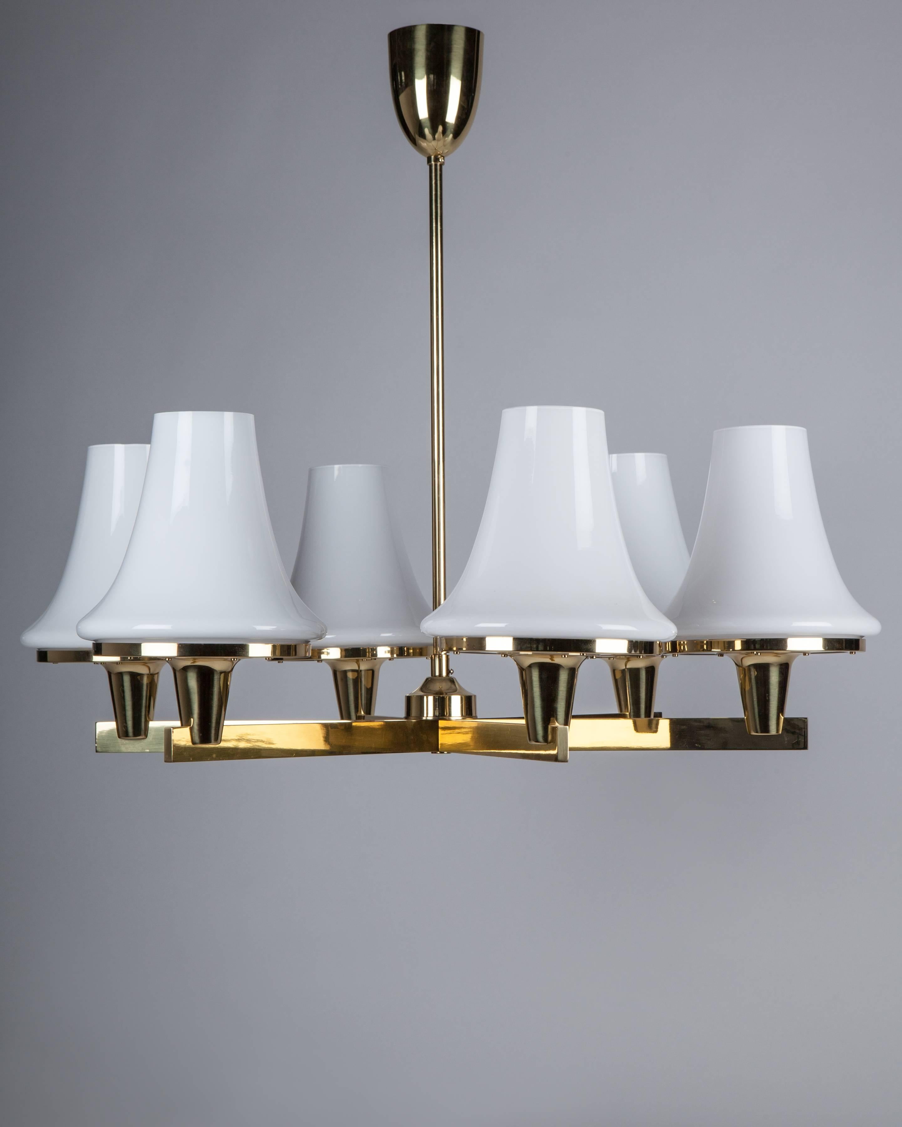 AHL4061
A vintage modern six-light chandelier in its original polished brass finish, each of the rectangular section arms terminating in a white glass tapered shade and Lucite diffuser. Signed by the Swedish maker Hans-Agne Jakobsson. Due to the