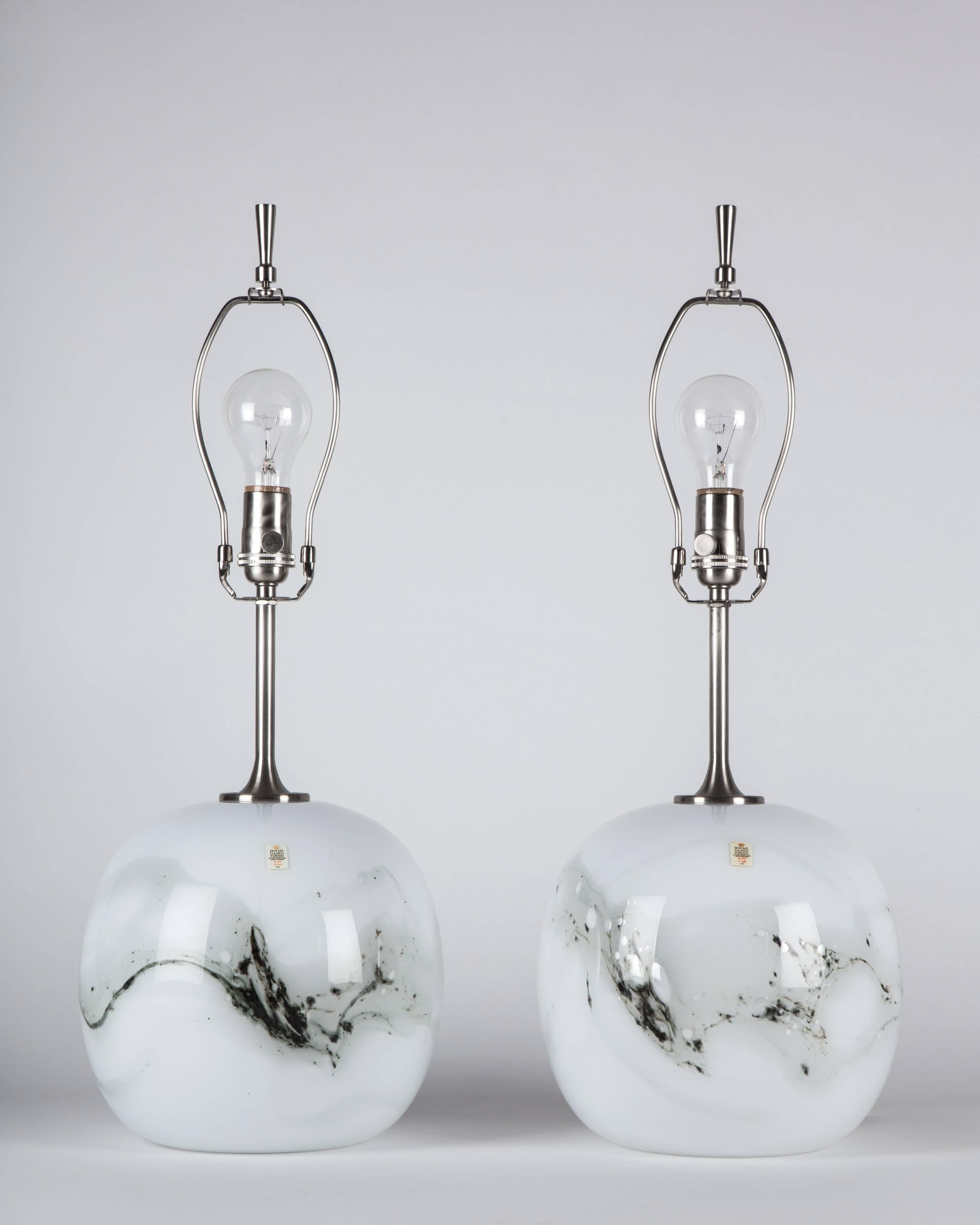 ATL1967
A pair of vintage cased white glass lamps with a black and grey design having satin nickel fittings. Designed by Michael Bang for the Danish maker Holmegaard. Due to the antique nature of this fixture, there may be some nicks or
