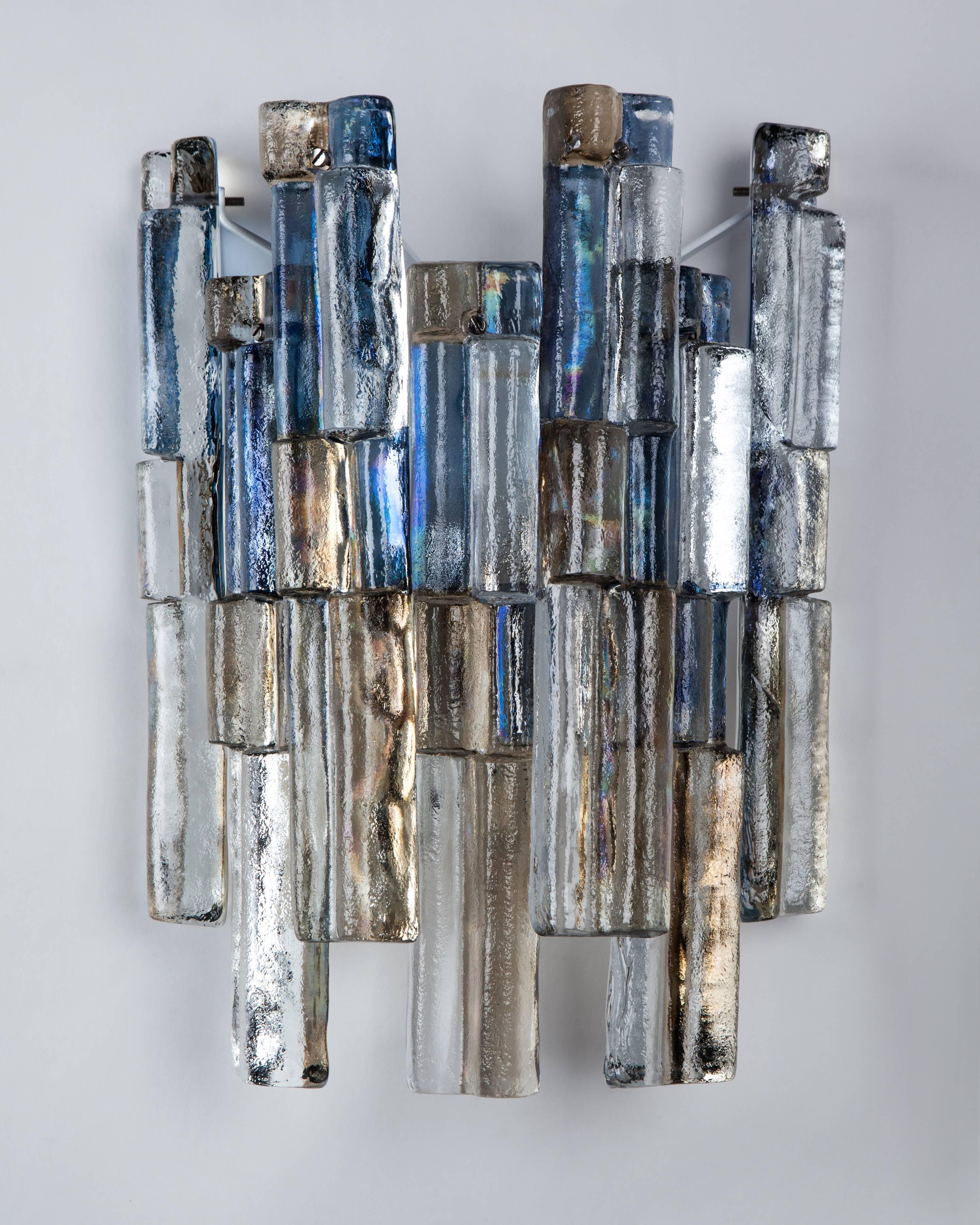 AIS3041
A pair of vintage sconces with cast glass elements having an iridescent blue tinted finish on white lacquer frames with polished nickel fittings. Signed by the Austrian glassmaker Kalmar. Due to the antique nature of this fixture, there may