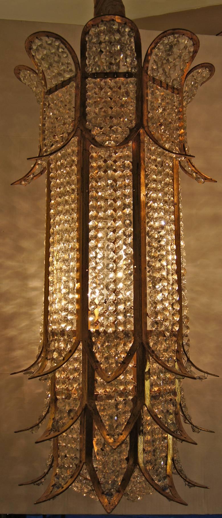 Conjunto de tres faroles de metal dorado y cristal con luces interiores. Los faroles con una corona de hojas de cristal moldeado. Pátina original. Se venden por unidades.

Medidas:
Caída mínima: 36
Diámetro máximo: 18