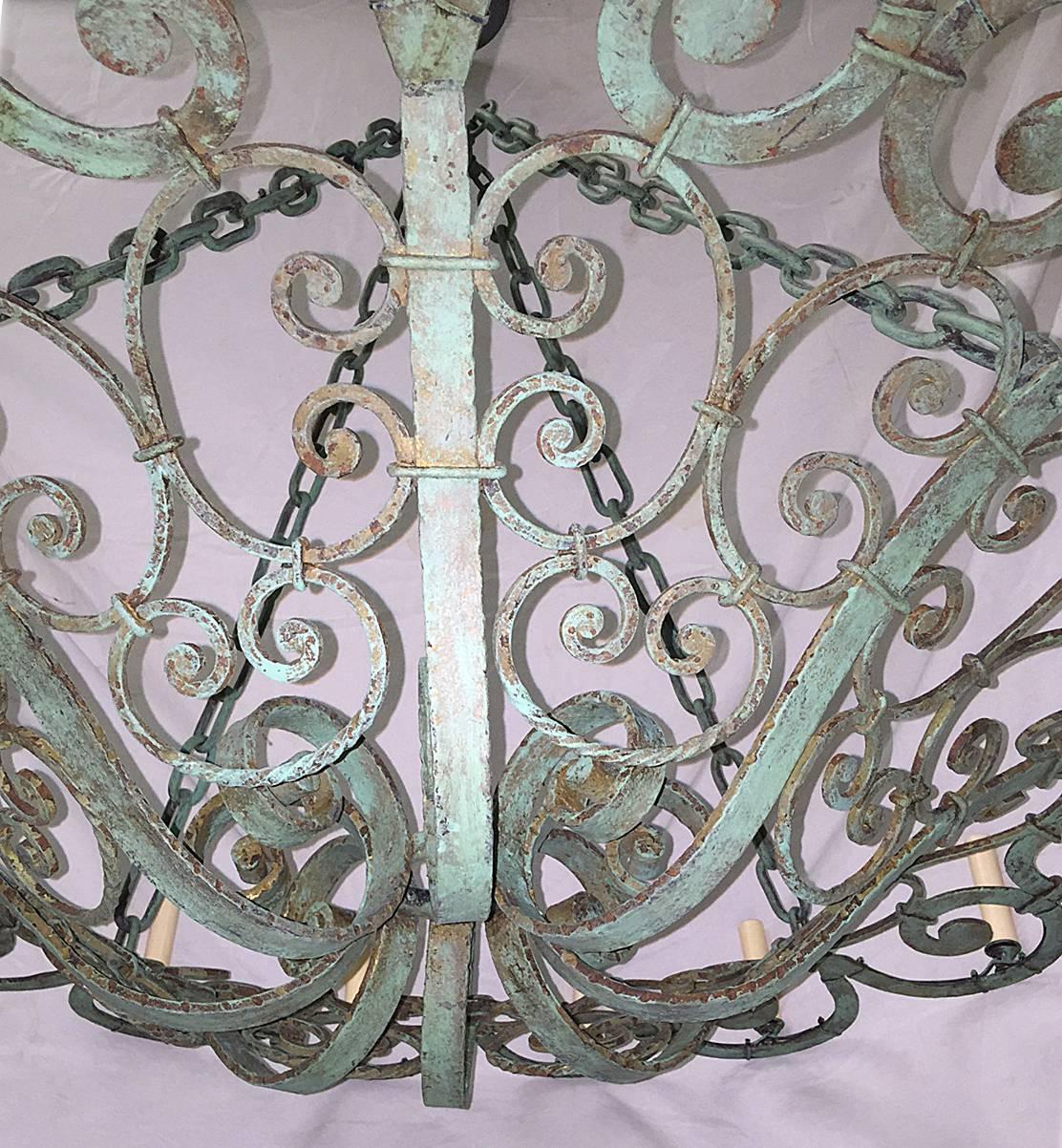 A French circa 1920s wrought iron chandelier with 16 lights, with painted finish. Body with scrolling motif, original patina. 

Measurements:
42