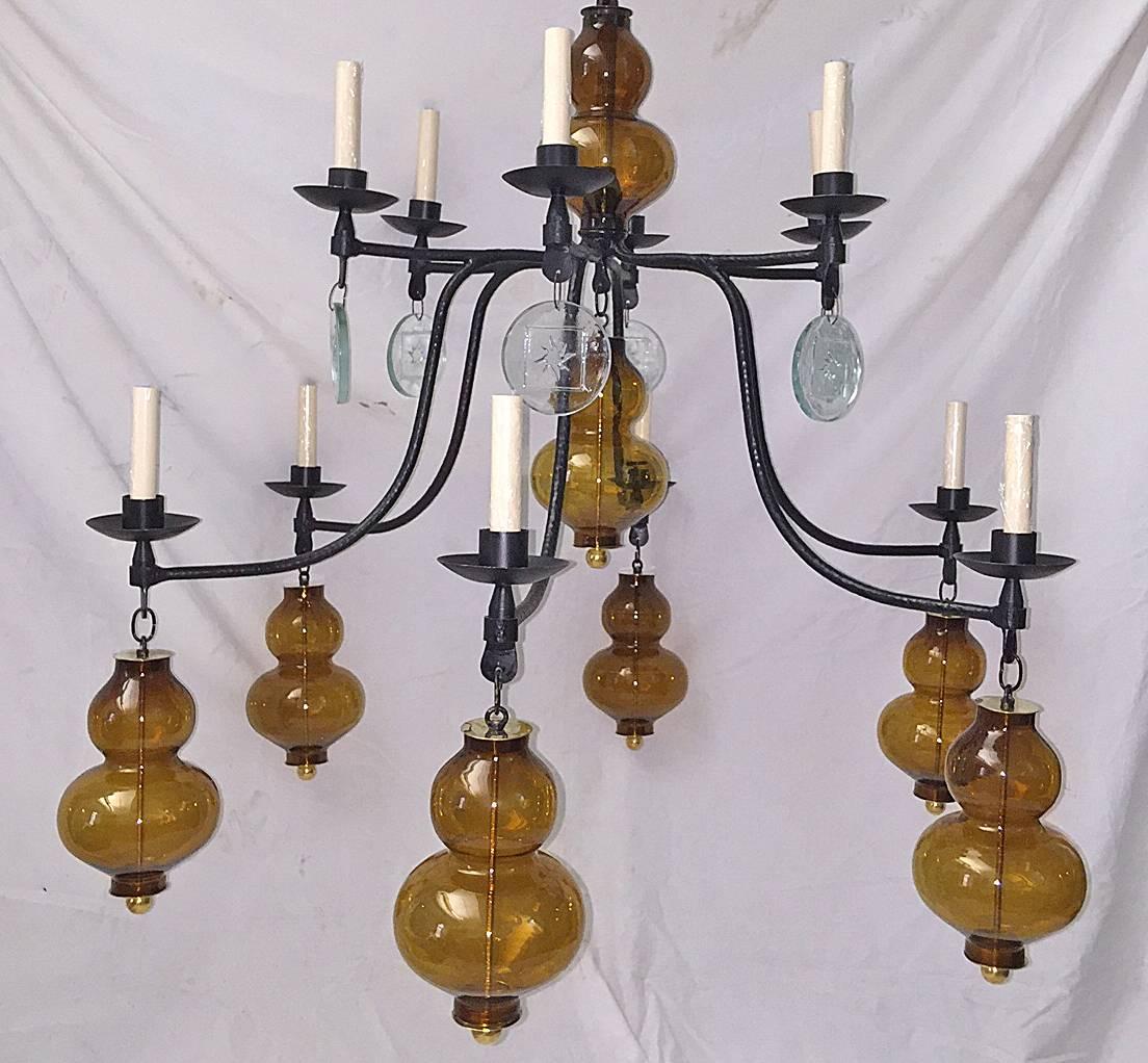 A circa 1970's large Swedish 12-light wrought iron chandelier with patinated finish, amber and clear glass globes and pendants.

Measurements:
Diameter: 44″
Drop: 45″