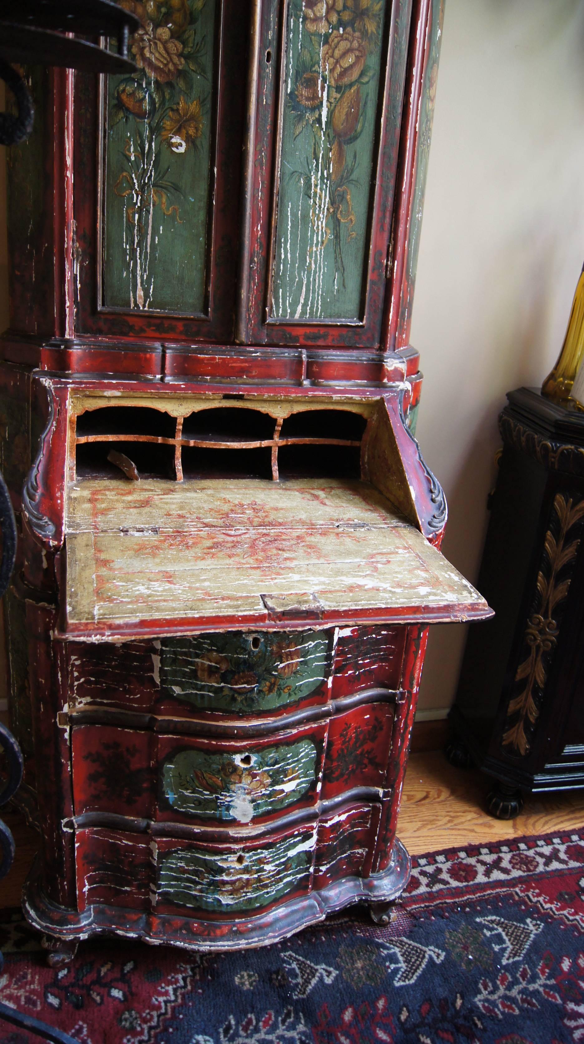 A painted Venetian secretaire with shelves and drawers on bottom portion of body.
 