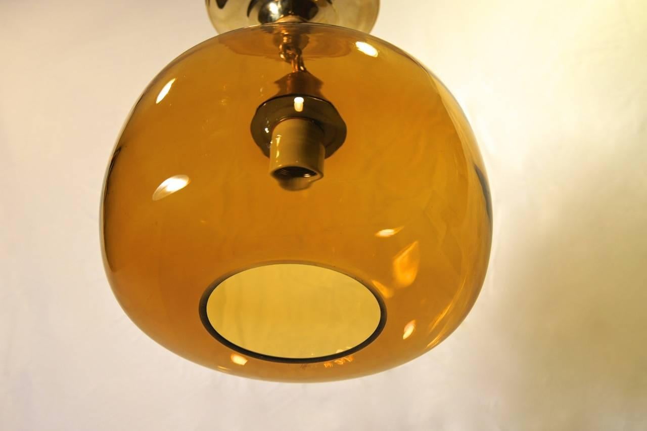A Mid-Century Swedish honey-colored glass pendant fixture with interior light. Two others available in different color glass - gray and blue. Sold individually.

Measurements:
Height (current drop): 12
