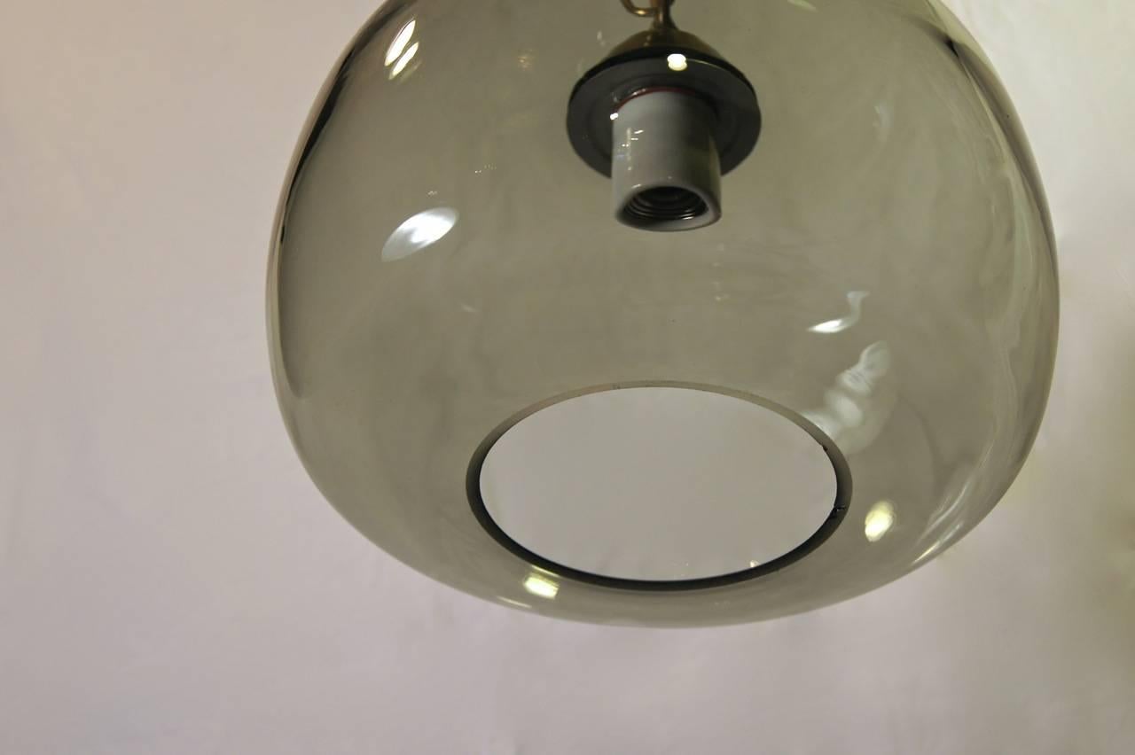 A Midcentury Swedish gray glass pendant fixture with interior light. Two others available in different color glass - blue and honey.

Measurements:
Height (current drop) 12