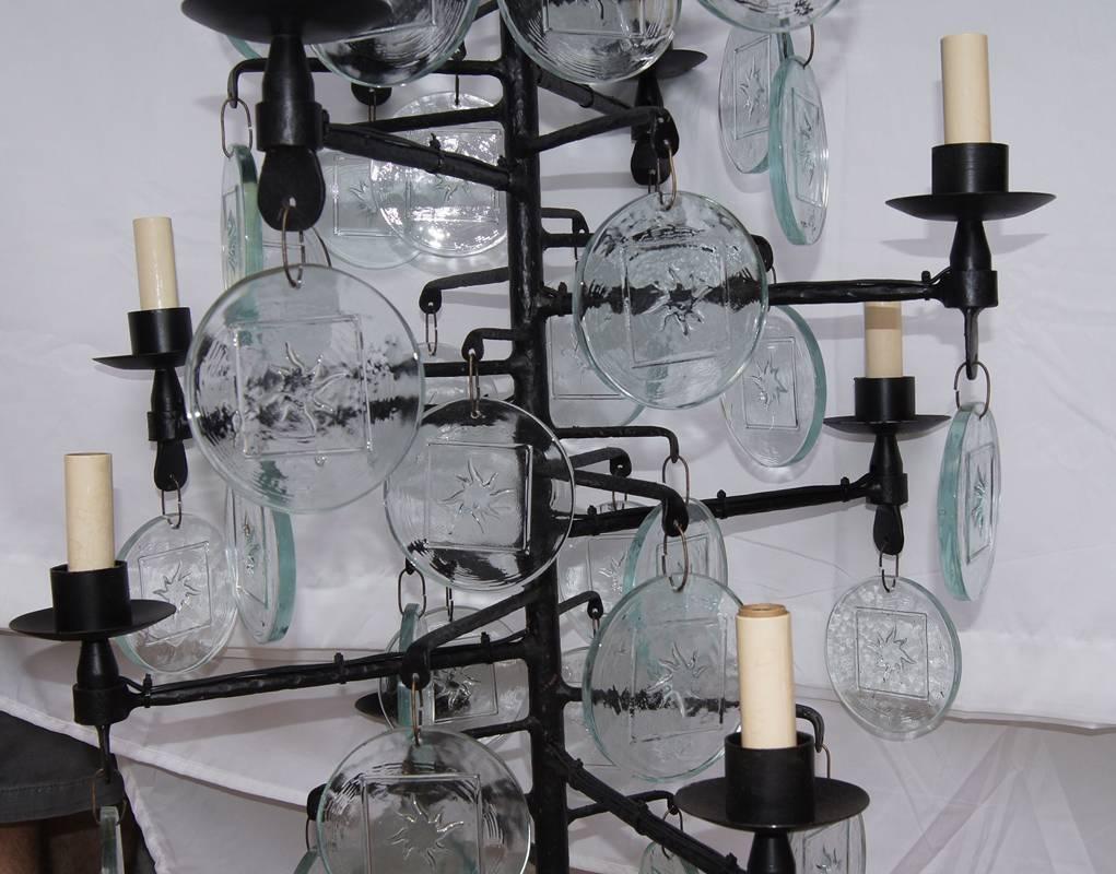 Pair of Swedish wrought iron and molded glass chandeliers, wired for electricity, with oversized glass pendants with a sun motif on center, circa 1960s. Ten candelabra lights each. Sold individually.

Measurements:
Min. drop: 47″
Diameter: 23″
  