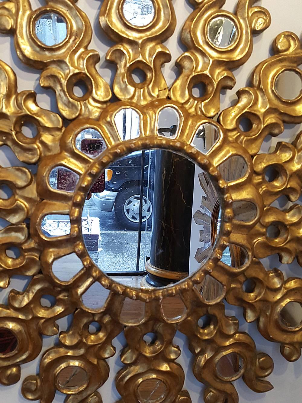 A circa 1930s Spanish gilt and carved wood mirror with mirror insets.

Measurements:
Diameter 25