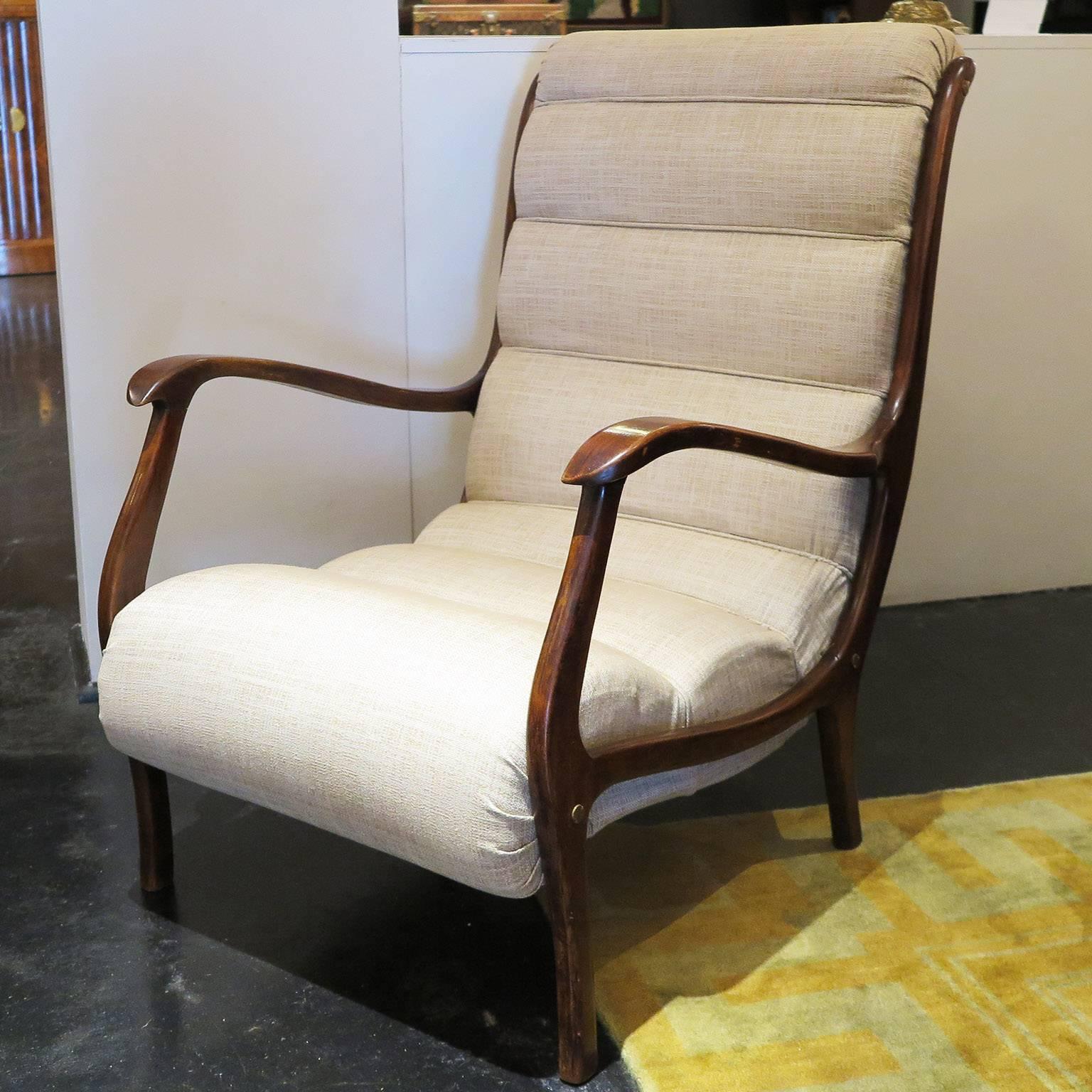 Pair of Mid-Century lounge chairs in stained beech wood with thin curved arms. The curved upholstery adds an unusual touch to the otherwise sleek chairs while keeping the seat comfortable. Chairs are in original condition.