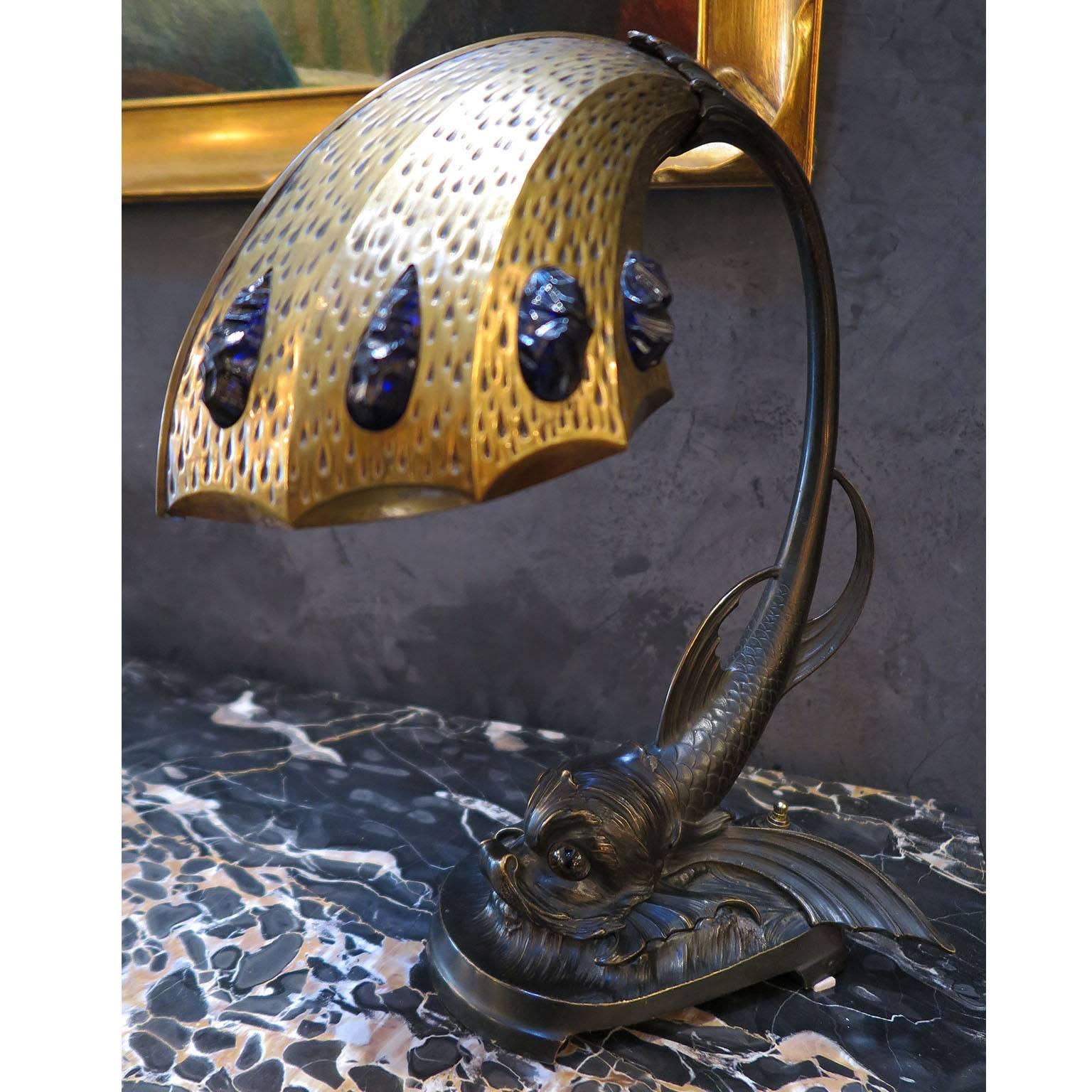 Rare Art Nouveau table lamp from France, circa 1900s-1910s. 
Dark bronze base in the shape of a fish with scales, fins, and large tale that leads into the stem of the lamp. The head of the fish is prominent with two glass eyes that light up from a
