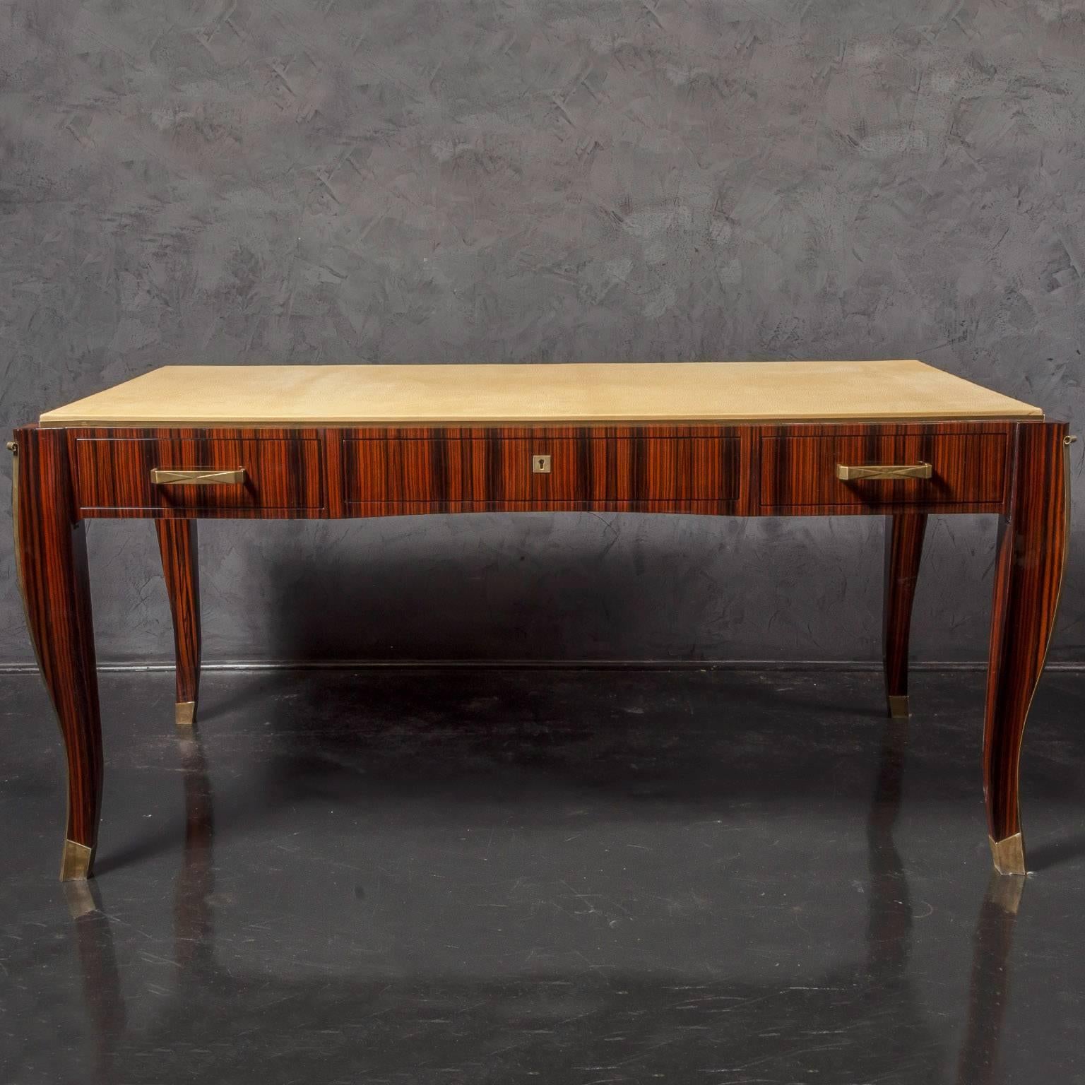 Beautiful Art Deco modern desk in Macassar ebony veneer with ostrich leather top. Brass detailing along the curved legs with brass feet caps and hardware. Custom size, veneer and details available.