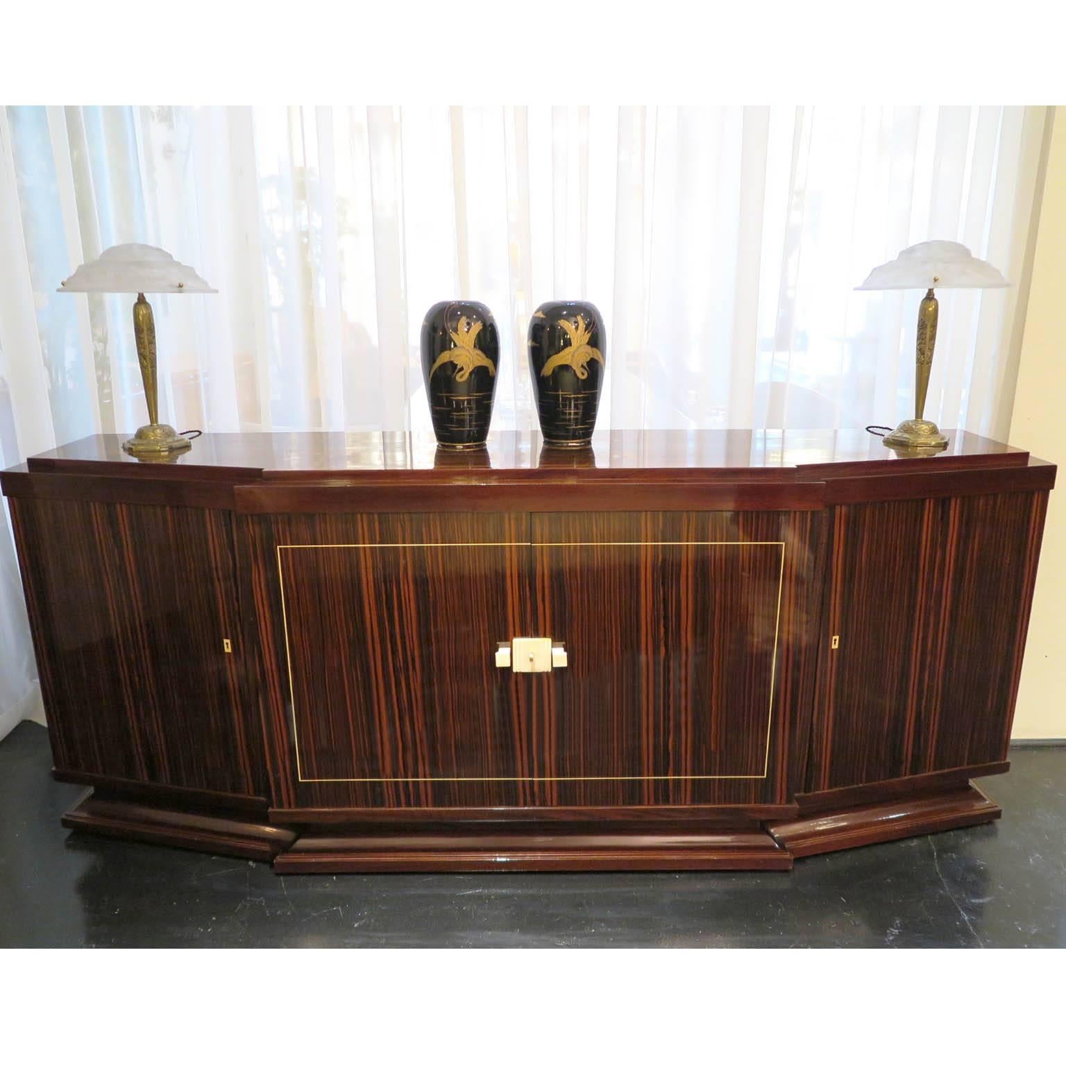 Elegant Macassar ebony sideboard with mahogany details. Original ivory hardware and thin inlayed ivory border around center doors. Signed by Majorelle on right side of piece. Slanted frame on sides with prominent middle doors. Shelving in center