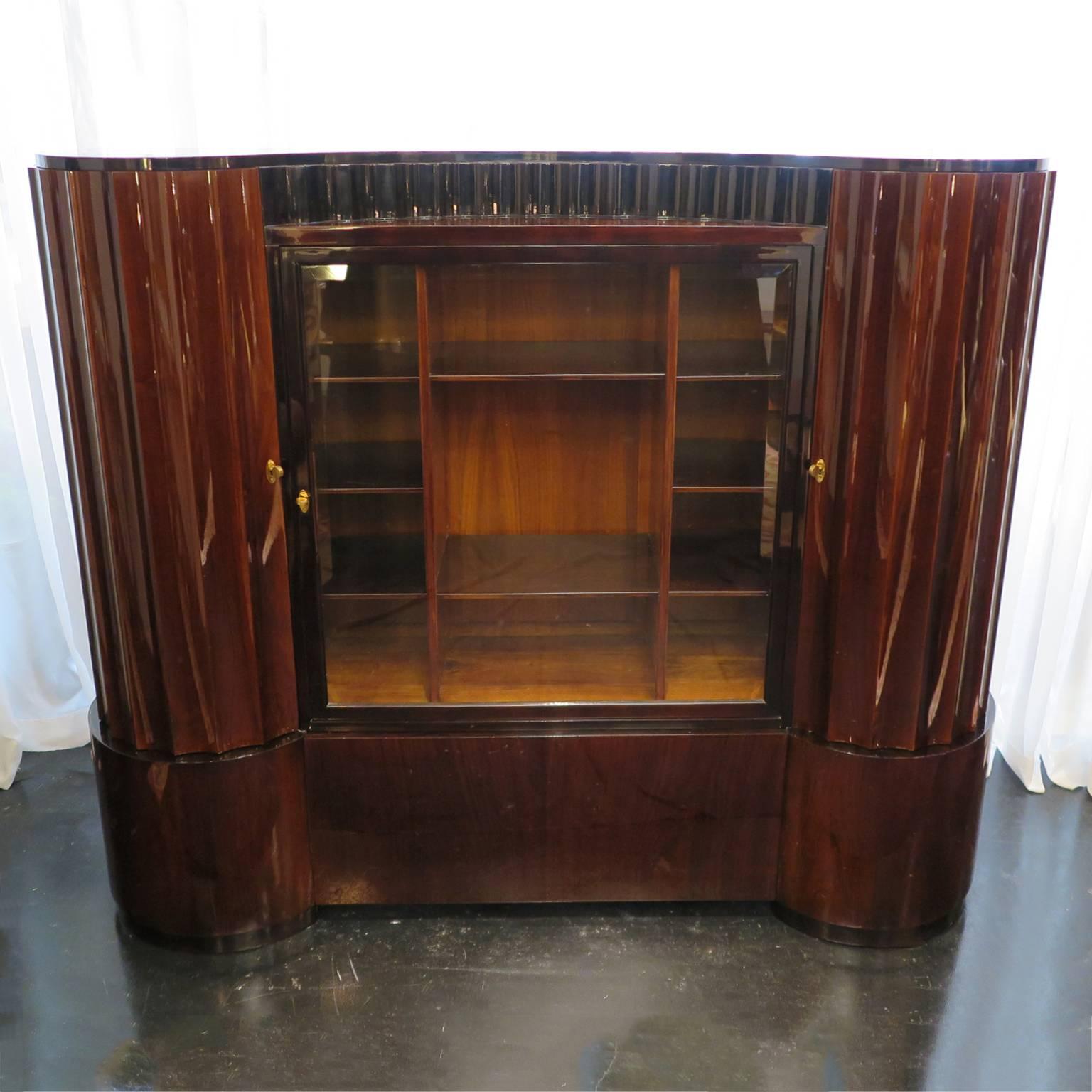 Lacquered palisander armoire by famed maker Francisque Chaleyssin (1872-1951). This impressive piece features rounded fluted doors with adjustable shelving inside and fluted details along the top of the frame. A stunning vitrine display occupies the