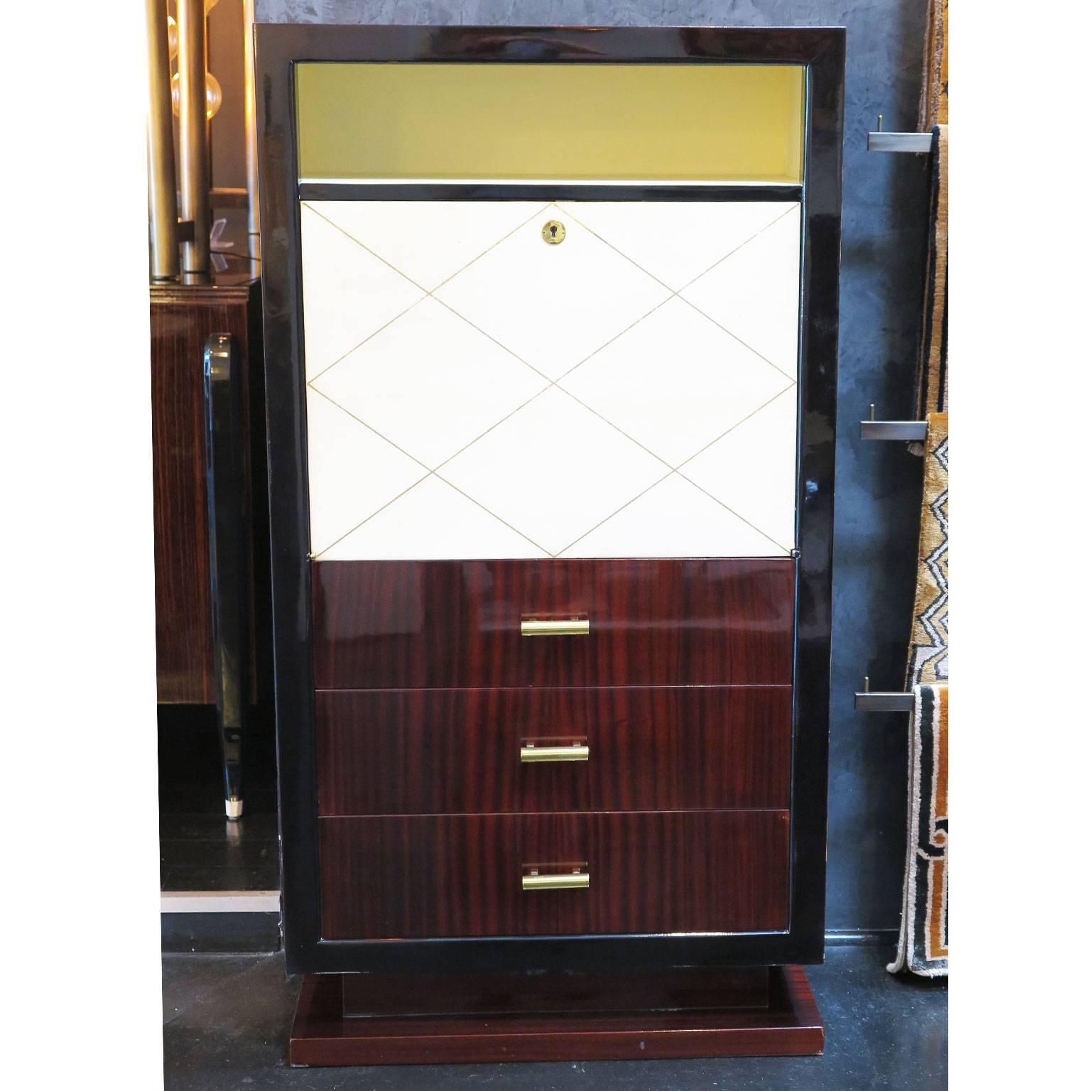 Tall Art Deco secretary in mahogany with dark stained border. Parchment door with gold leaf criss cross design opens to writing table with interior compartments. Three drawers with original brass hardware. Shelf above parchment door for more storage.