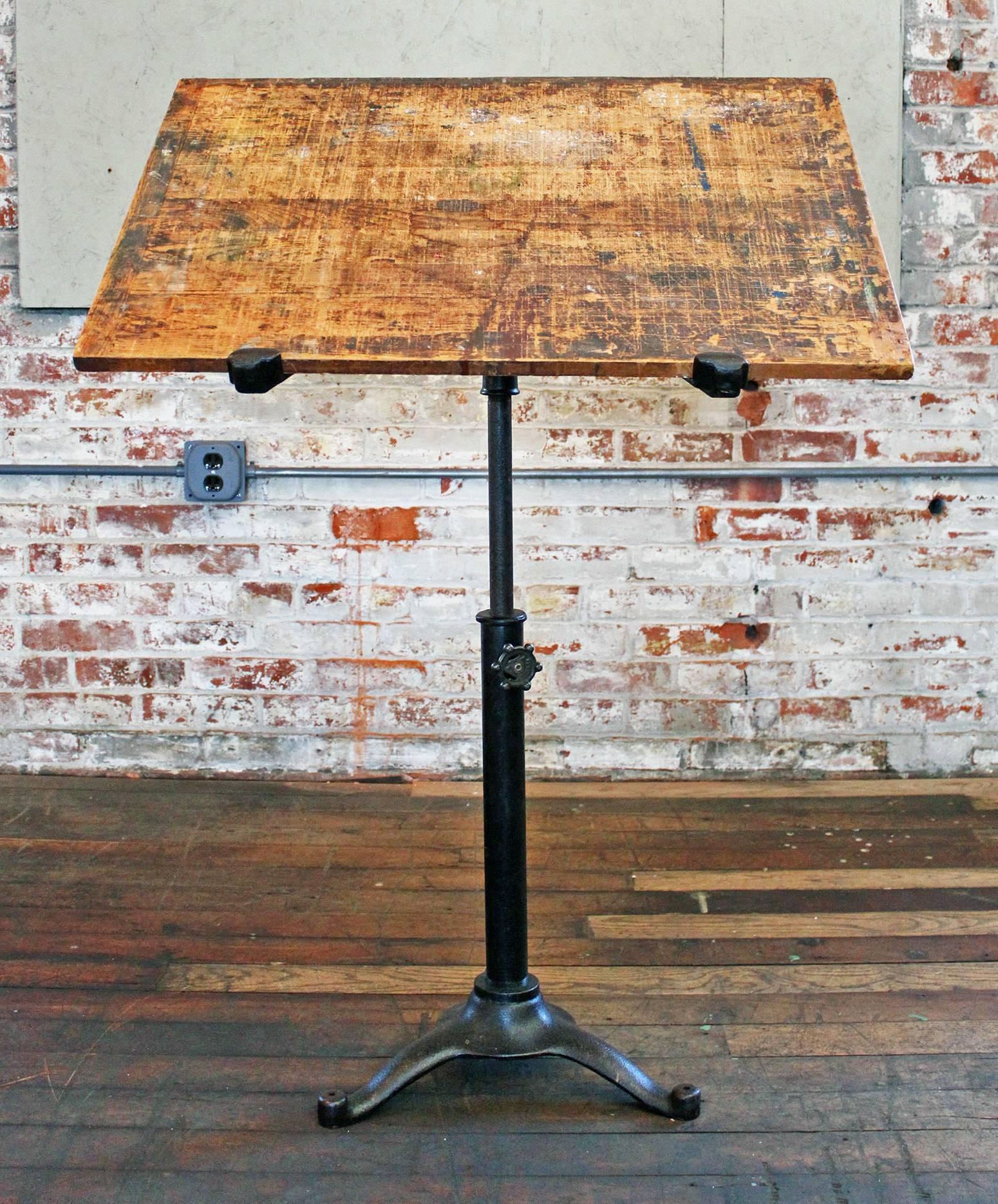 Cast iron and wood Industrial vintage adjustable tilt top artist, drafting table, pedestal music stand, stamped "Artists League of Pittsburgh PA." The wooden top measures 31" x 23" x 3/4". Overall height is adjustable from