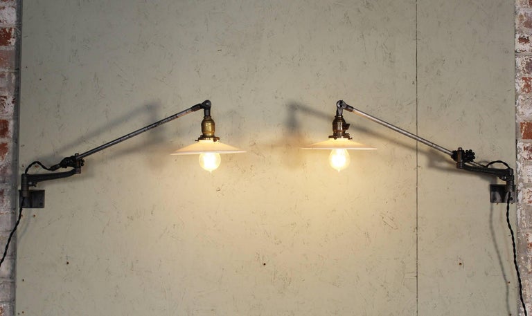 Pair of vintage industrial milk glass O.C. White wall task lamps, bedside lights or sconces. Articulating lamps that feature cast iron knob adjustment fittings, authentic antique milk glass shades and fitted with Edison bulbs. Milk glass shades