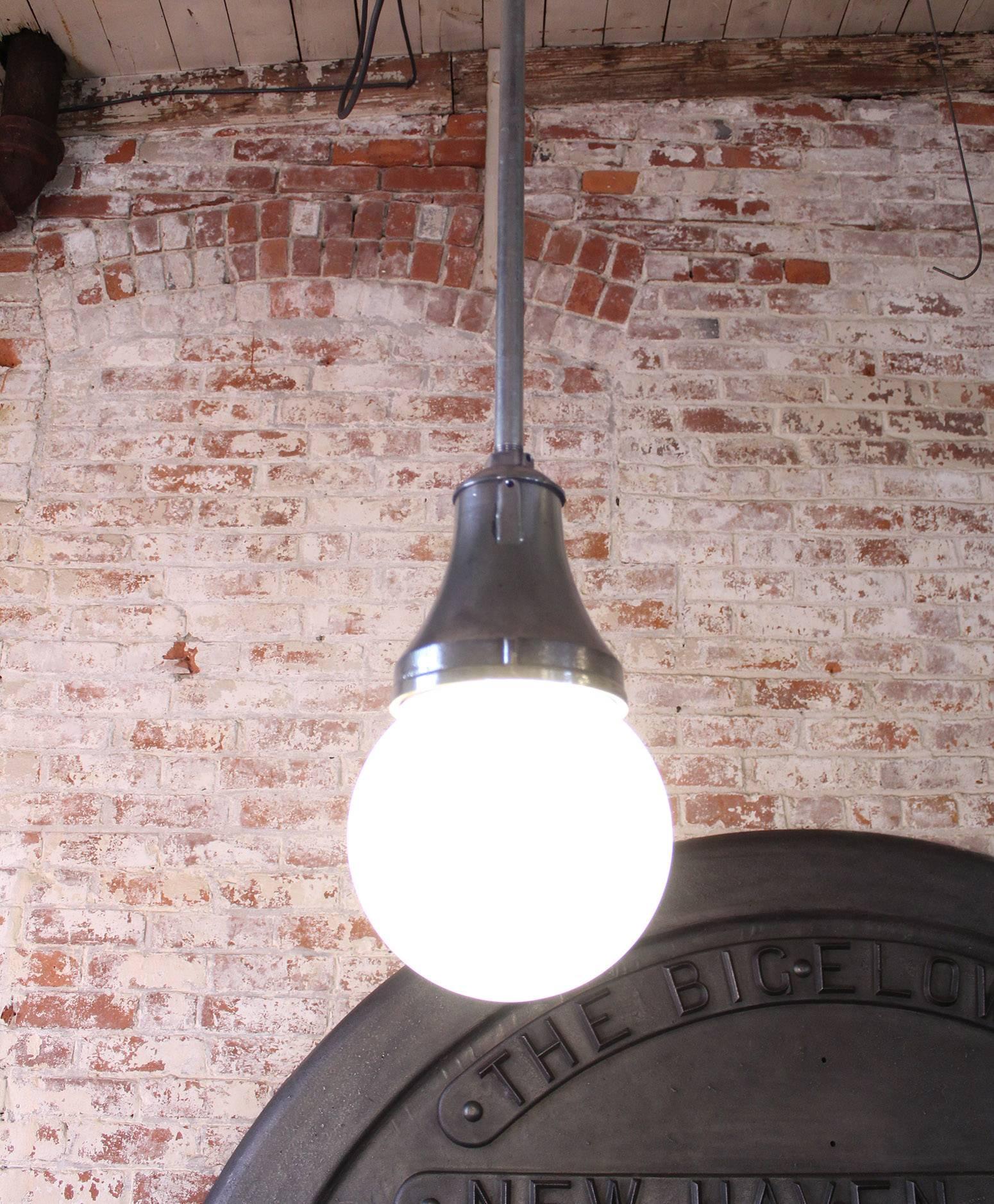 Cast iron, steel and frosted white glass globe industrial hanging, ceiling pendant lamp, light. The glass measures 8