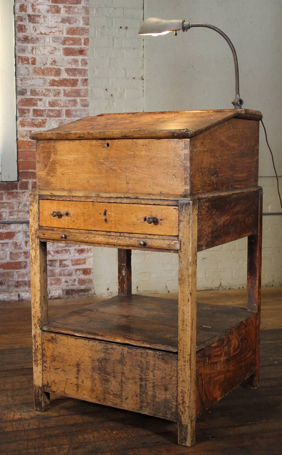 Vintage industrial wooden host, hostess, maître d', greeting stand, standing desk. Hinged top opens to reveal storage with small drawer and cubby holes, bottom opens for storage, and mid-section features a drawer and solid pull out writing shelf.