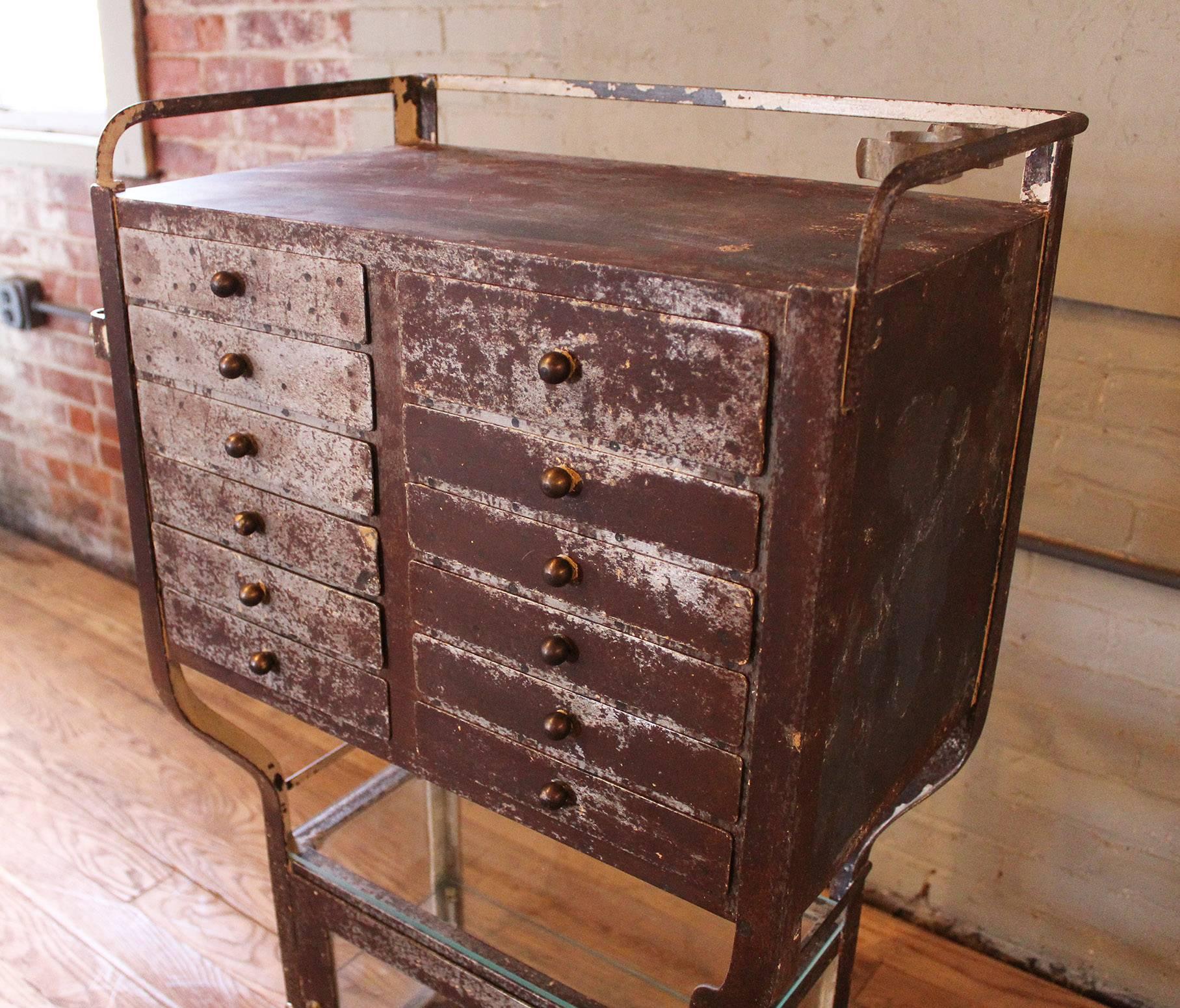 Rusted and painted metal and glass rolling medical cabinet - stand - cart on double swivel castors. Overall dimensions are 21 7/8