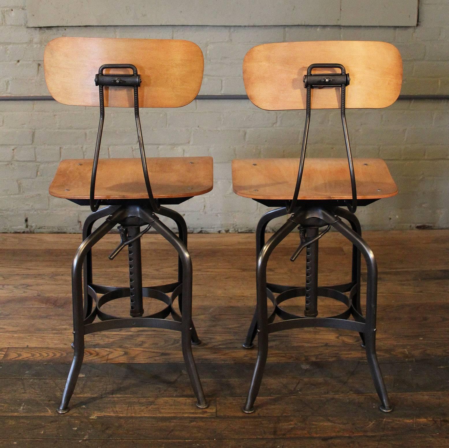 Pair of bent plywood and steel, metal vintage Industrial toledo adjustable swivel bar stools, chairs. Overall height adjusts from 36" - 42 1/2". Seat height adjusts from 22" - 29 1/2", seat width measures 16", depth measures