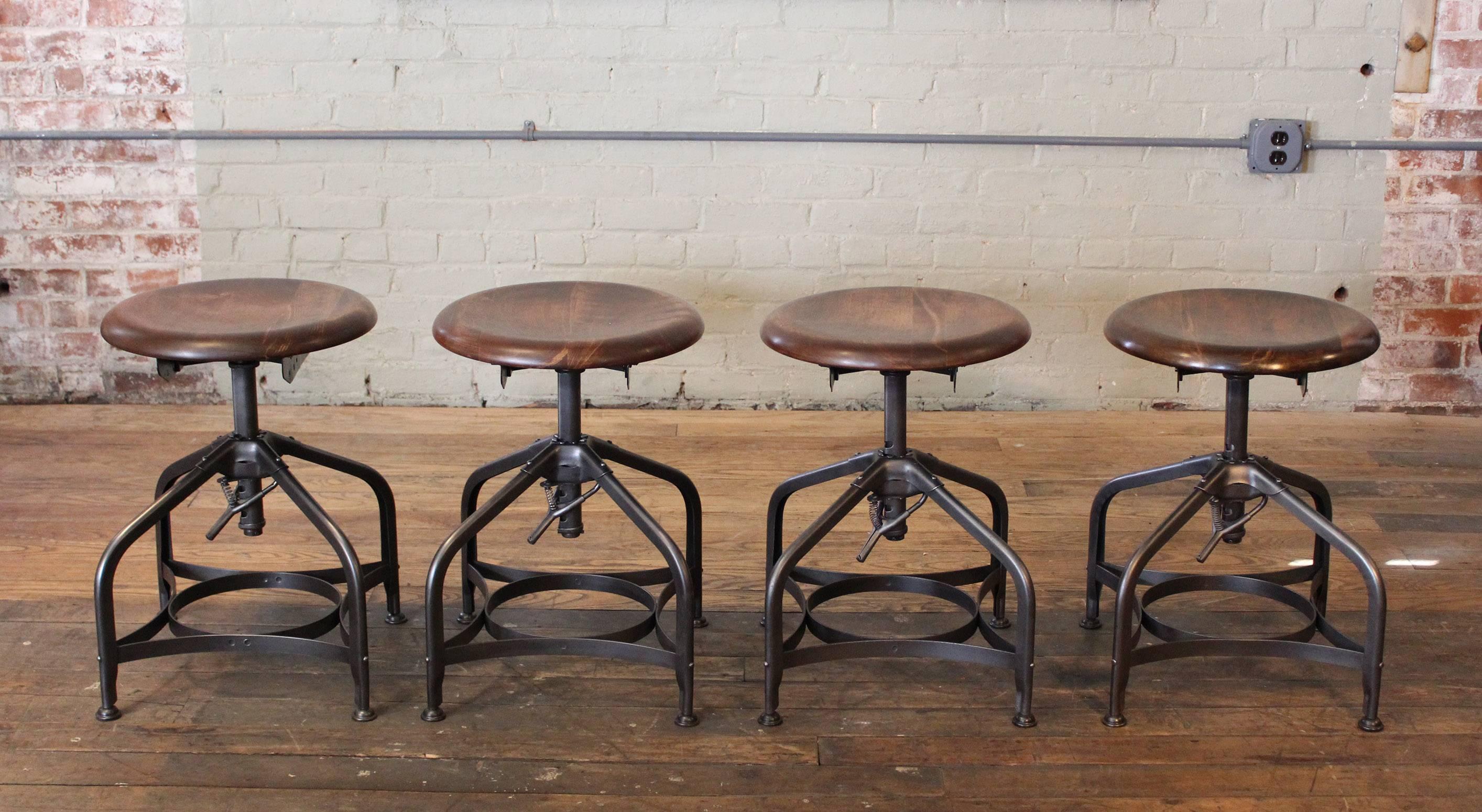 Set of four steampunk vintage industrial adjustable toledo wood and metal shop stools. Seat measures 17 1/2" in diameter, and measures 1 3/16" thick. Seat height is adjustable from 17 1/2" - 22 1/2". Base measures 15 1/4" x