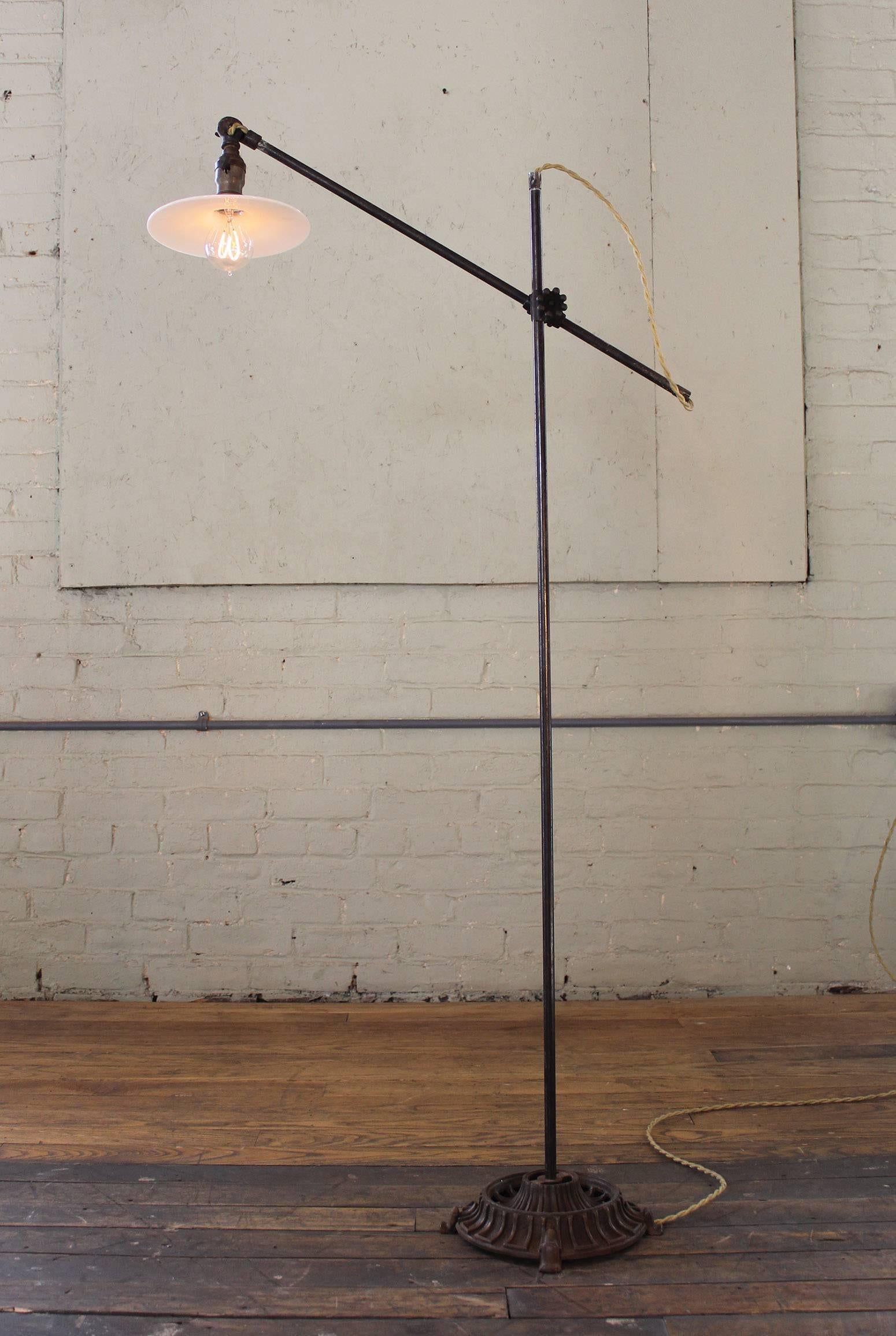 Milk glass adjustable vintage Industrial reading floor, task lamp, light with exquisite cast iron base. Shade measures 7 3/4" in diameter, top arm measures 26" in length, bottom arm measures 50 1/2" in length, and base measures