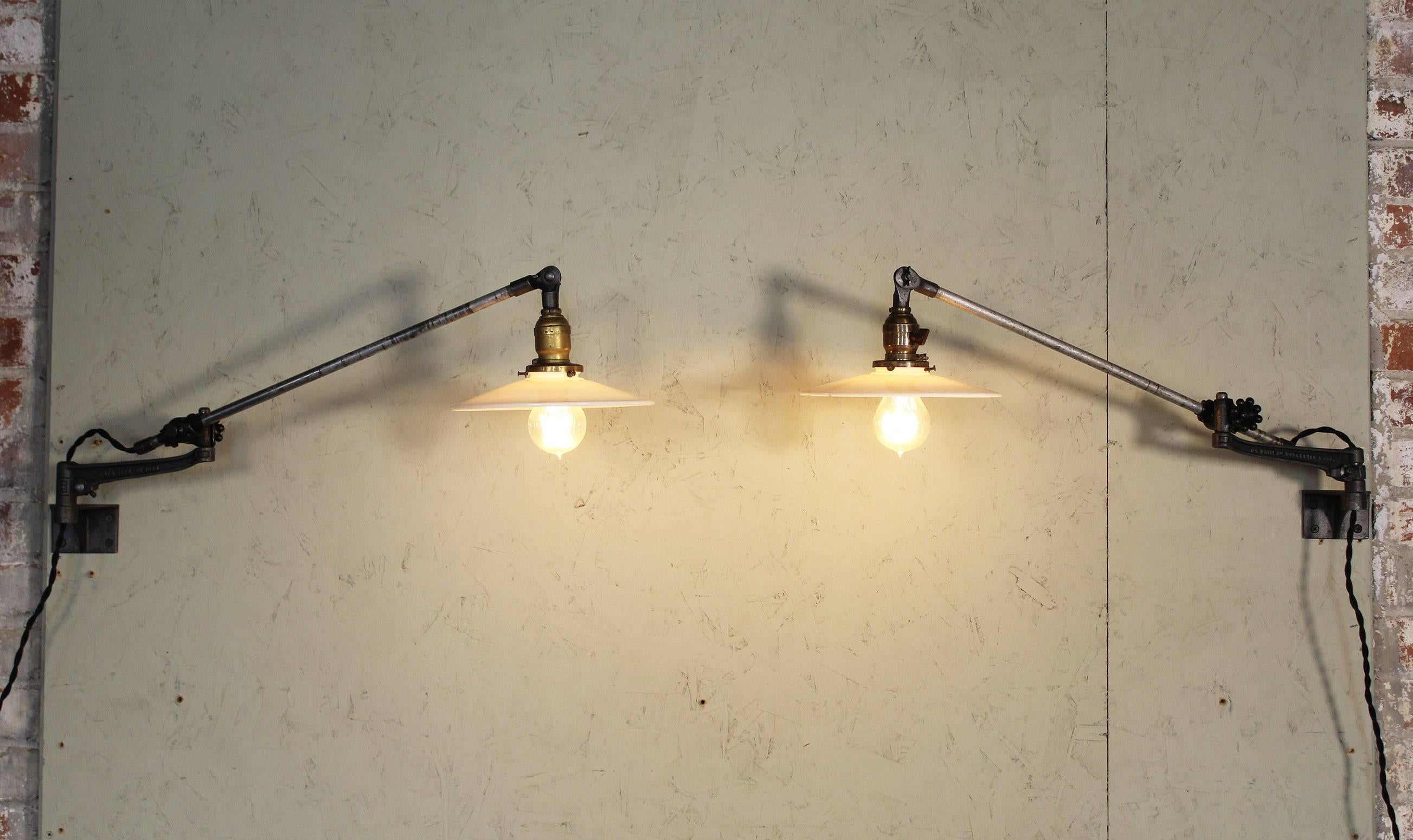Pair of vintage Industrial milk glass O.C. White wall task lamps, lights with Edison Bulbs. Articulating lamps with cast iron knob adjustment fittings. Milk glass shades measure 8 1/4
