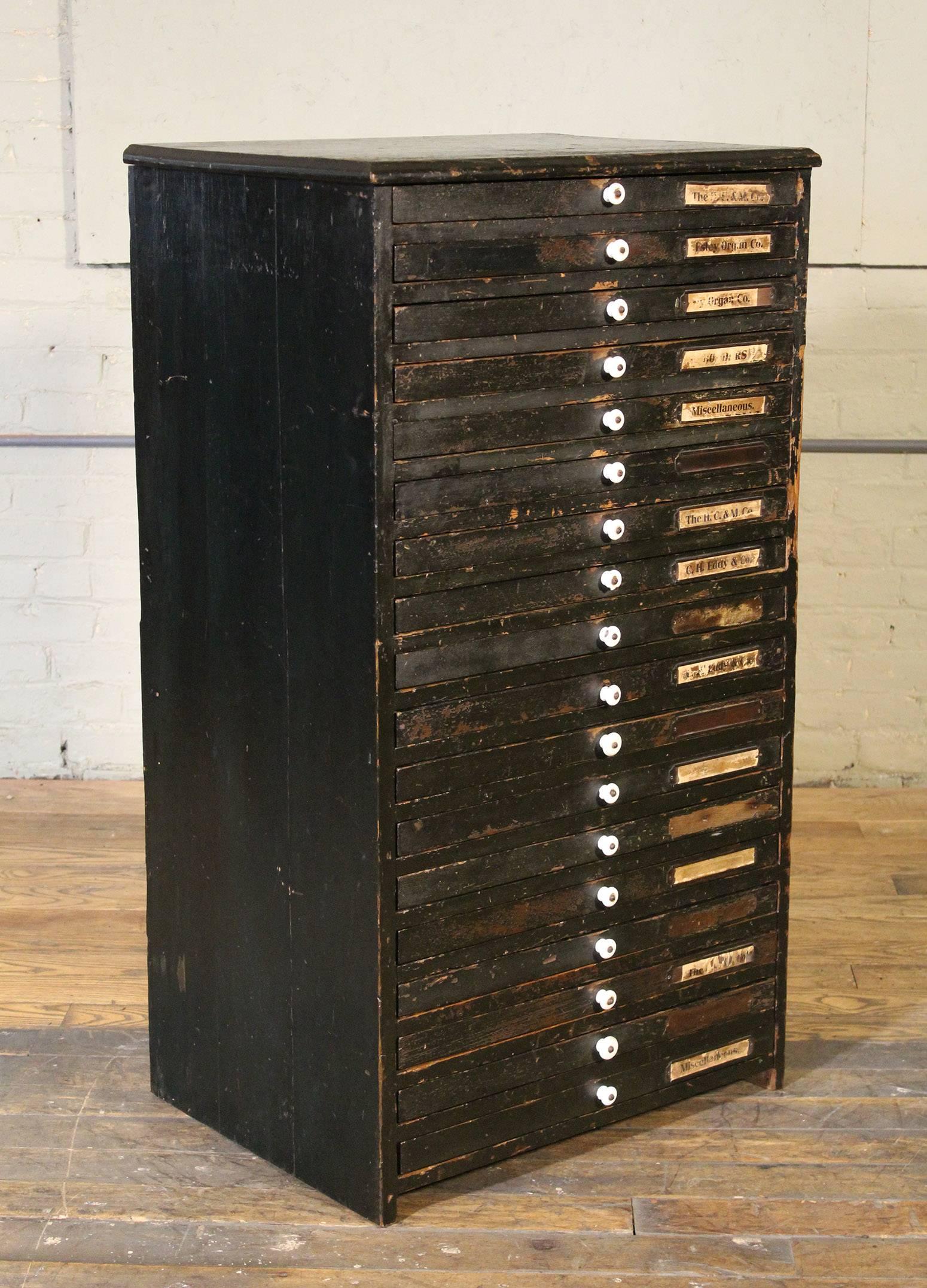 Vintage Industrial multi-drawer distressed wood flat file storage cabinet. 18 drawers, eight of which are lined with a single piece of wood down the middle. The rest have different configurations from full width to many small compartments.