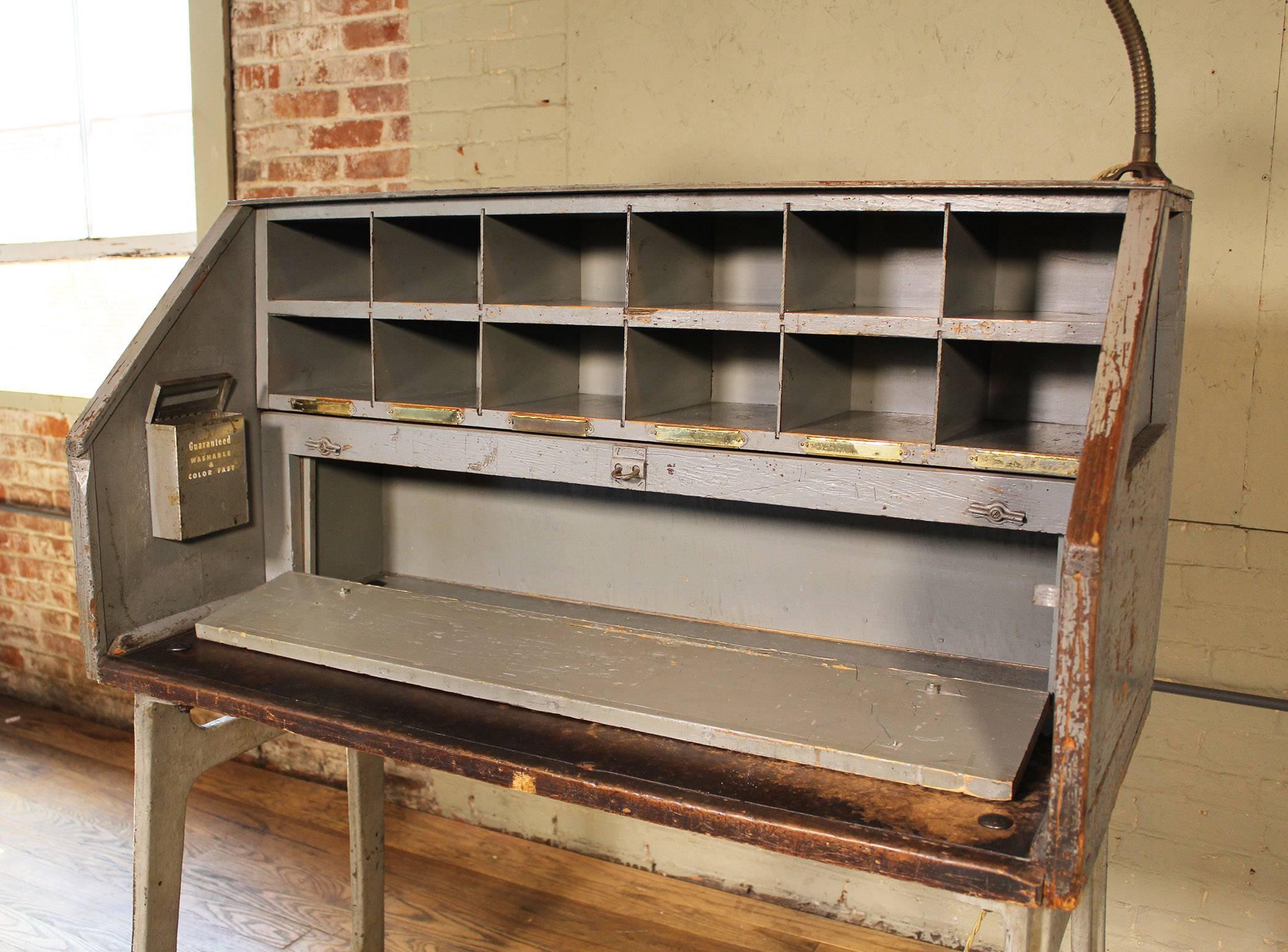 Vintage Industrial cast iron and wood foreman's shop desk. Includes adjustable goose neck lamp. Desk has 12 cubby holes and a fold down lockable shelf for storage. Desk work area measures 38 1/4" x 11 1/4 x 33" tall. 31 3/4" to