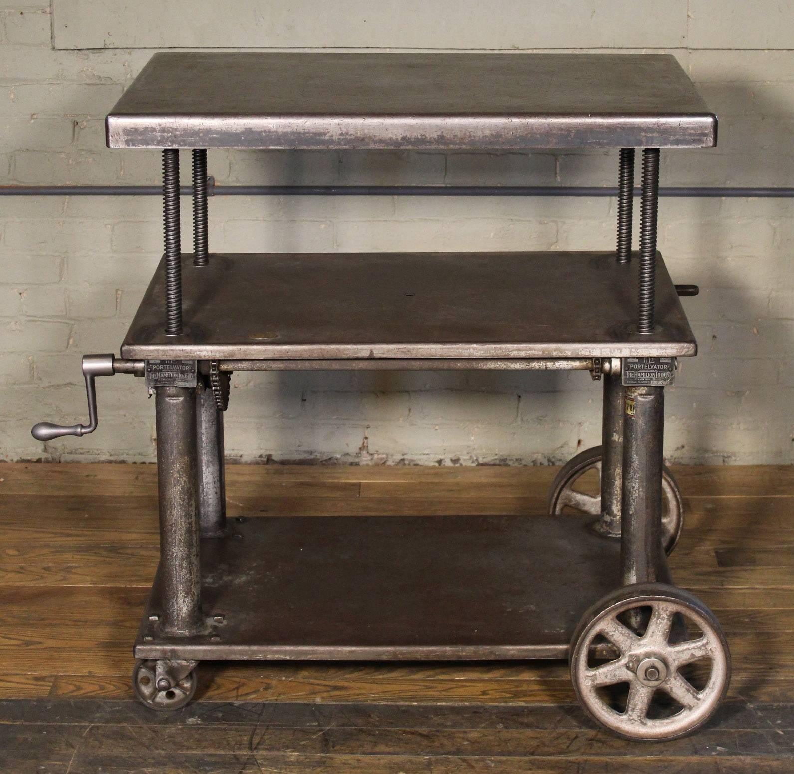 Original vintage Industrial adjustable metal, steel rolling three tier lift bar cart / table with cast iron casters / wheels. Measure: Top is adjustable in height from 25 1/4" - 41 1/2". Top measures 34" x 22". Shelf heights
