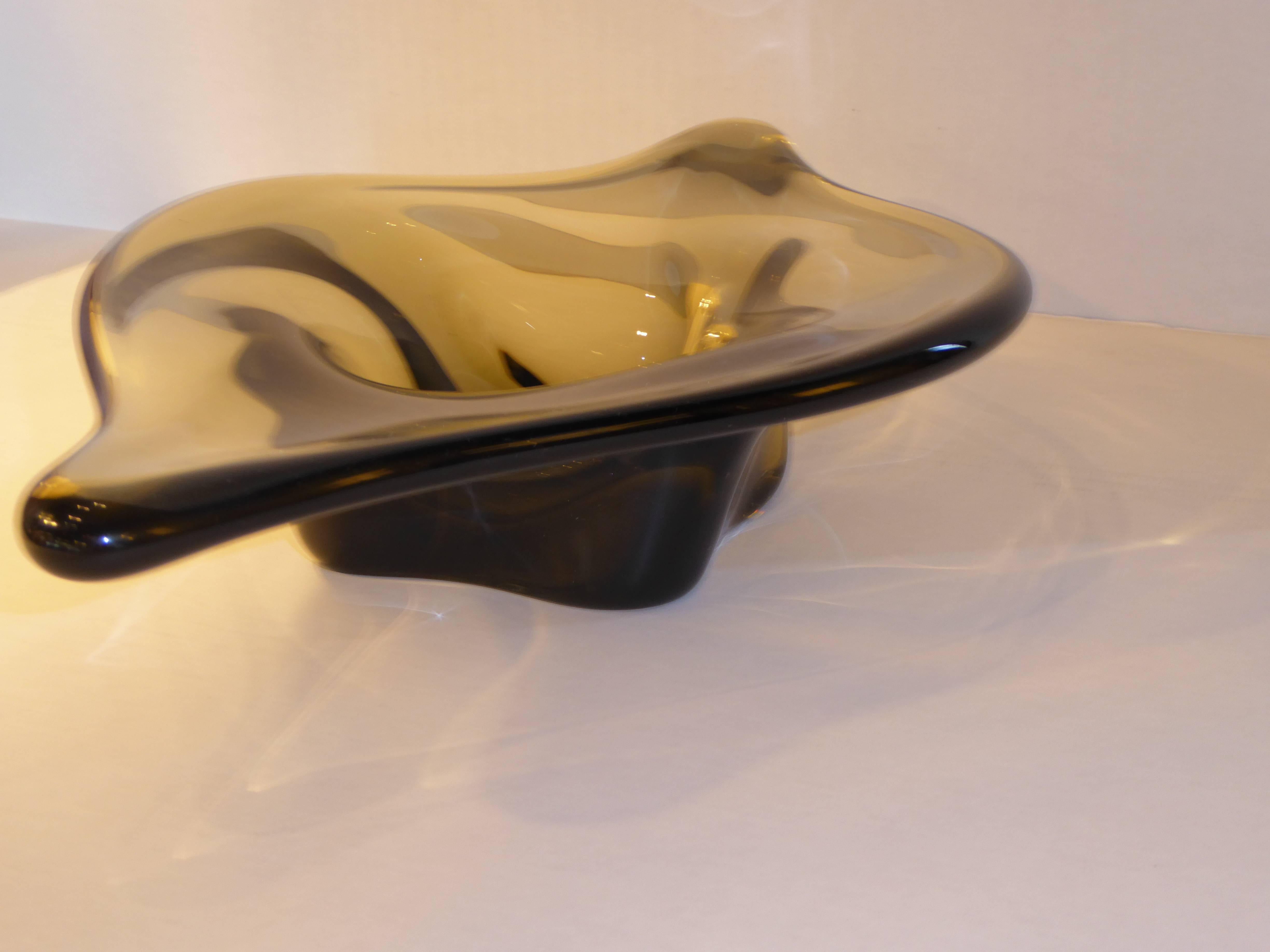 Rising from a thick glass base, free-form glass flowing outward, this Murano blown smoked glass vessel or bowl has a beautifully strong presence. Thick, heavy glass appears to be alive.

Measurements:
15 3/4" wide x 9 3/4" deep x