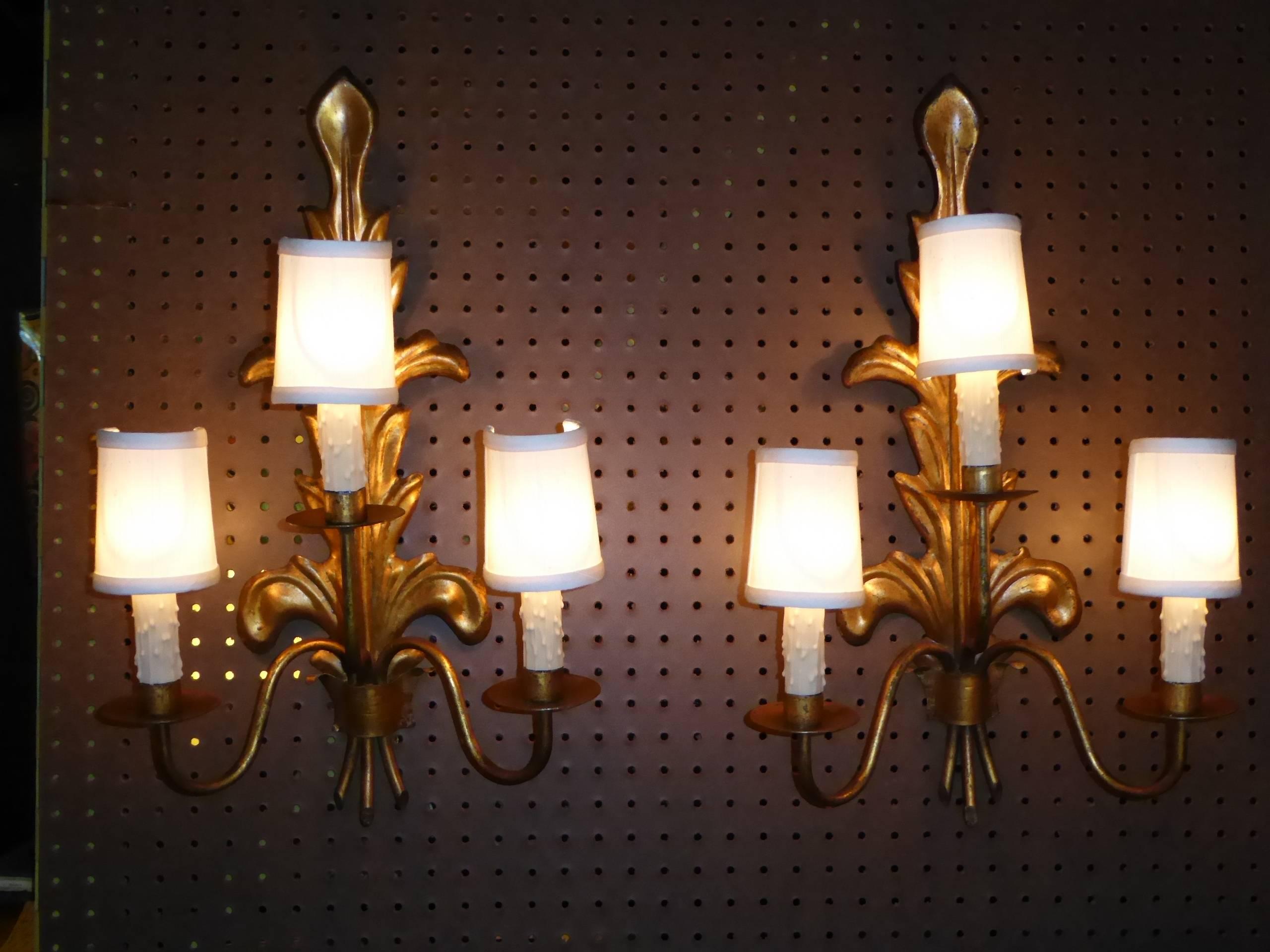 REDUCED FROM $1,200....Fine Mid-Century appliques from Barcelona. Acanthus leaf in gilt tole backs with three curling branches ending in bobeches and wax drip candles. Rewired and with new UL candelabra sockets. 40 watts max each. Crossbar in back
