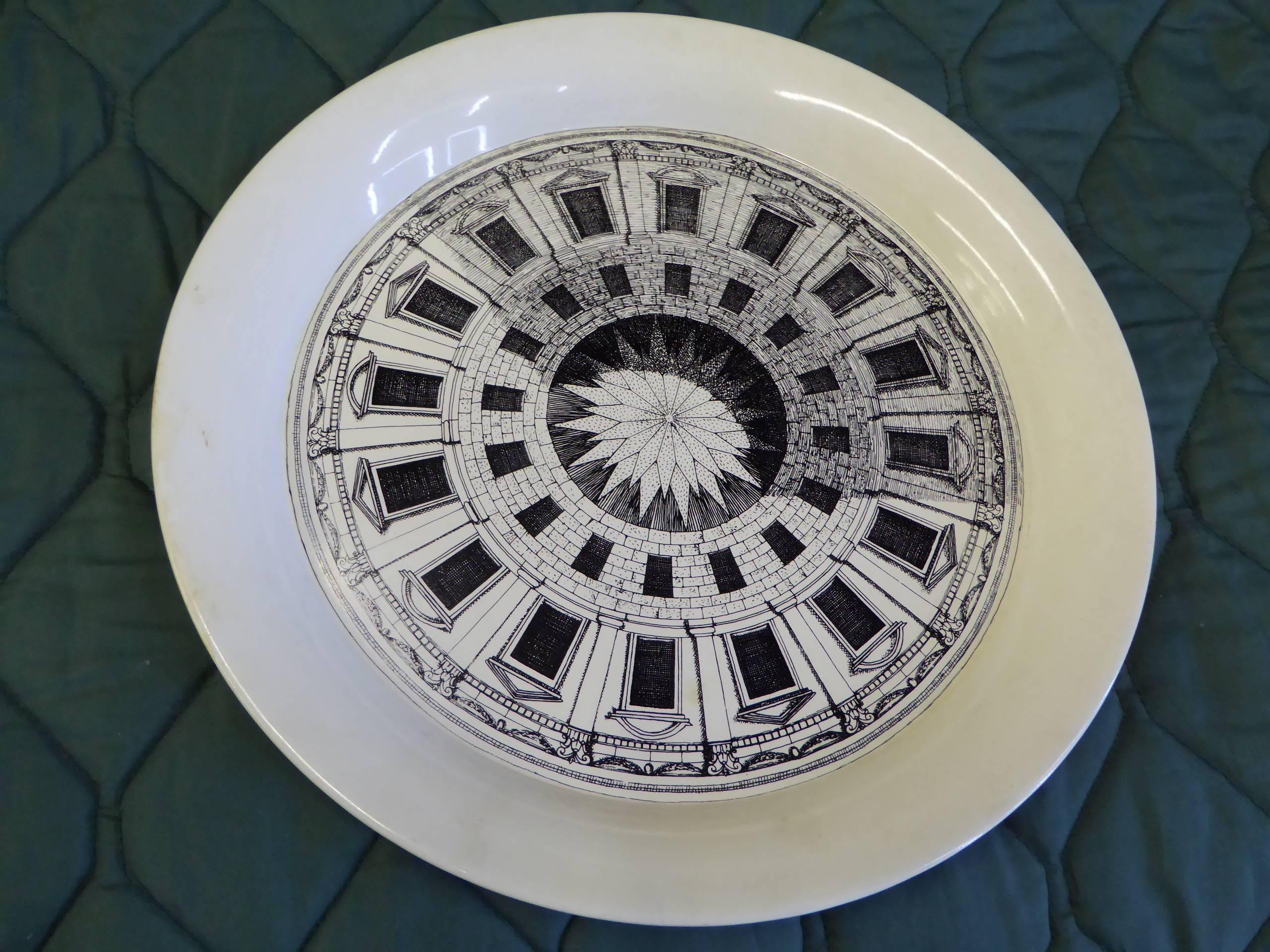 Piero Fornasetti created the Cortile designs in 1954. Showing polygonal courtyards, seen from above, they differed from the dome designs which are seen from below. This metal tray from his studio features a rolled edge in antique cream enamel with
