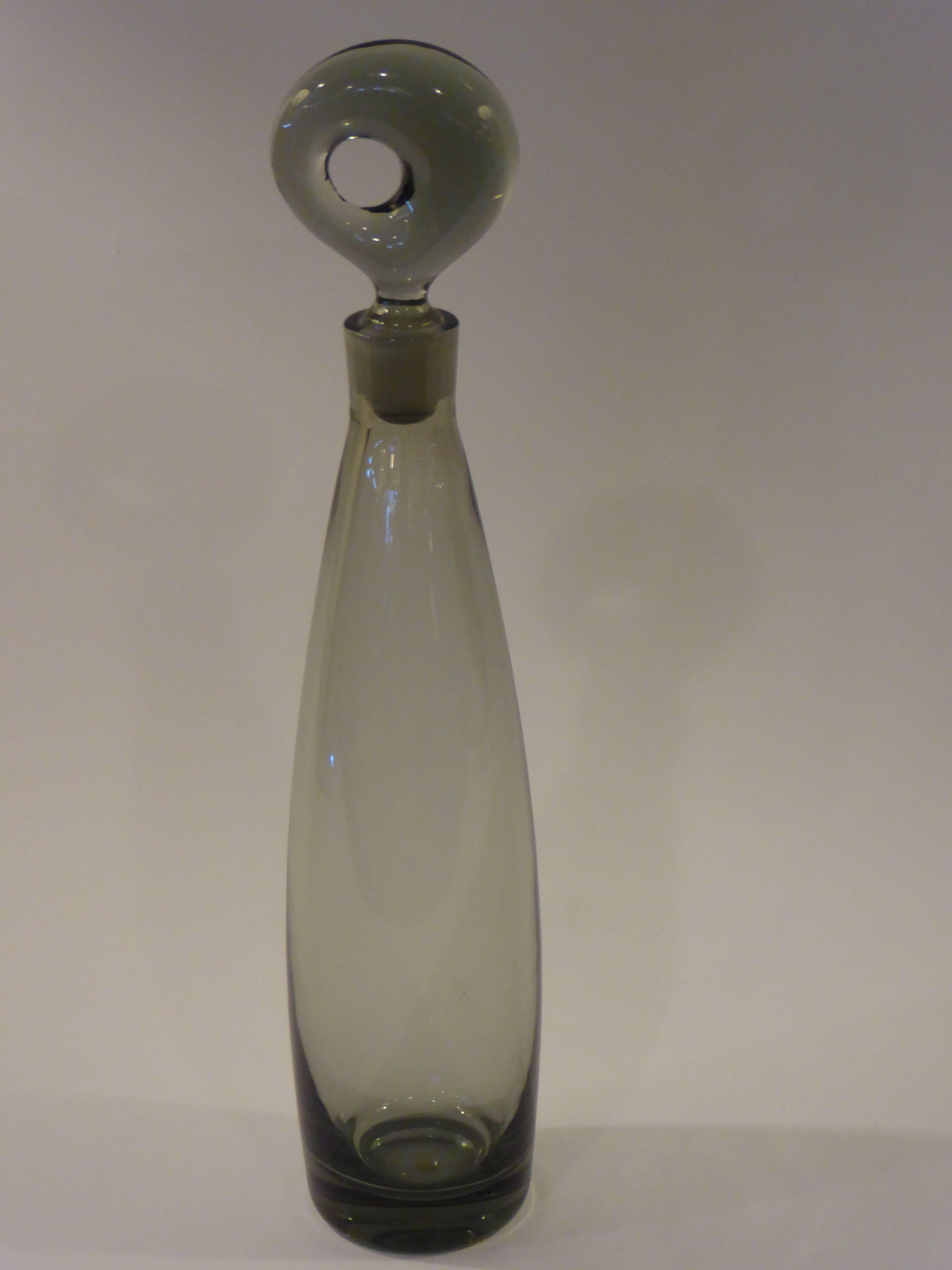 Designed by the gifted Director of Design of many years for Holmegaard in Denmark, this decanter in smoked blown glass is a Mid-Century classic. Exceptional organic form. Excellent condition.
Measurements: 15" high x 3 1/4" diameter.