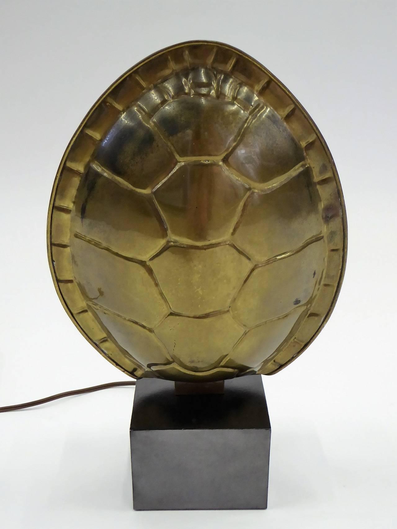 From 1978, a dark patinated brass turtle shell lamp. Standing on a black metal base with built in dimmer switch. Remnant of Chapman label. Extra long cord. New UL inner socket. Perfect shelf lamp and wall wash.