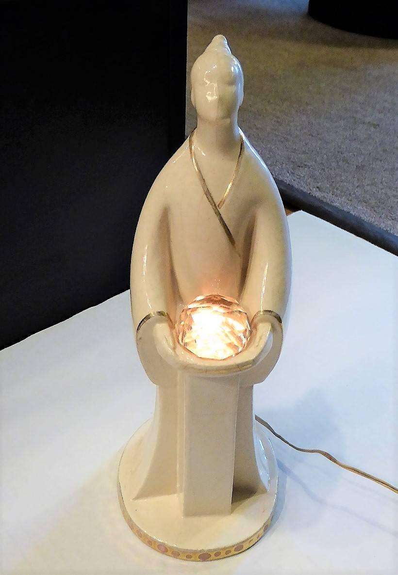 Off-white ROBJ porcelain figural lamp of a mystic holding a faceted crystal. With subtle gilt trim. Working beautifully with original lighting, wiring, push-button switch and French plug with American adaptor. Signed in the clay on the bottom, ROBJ