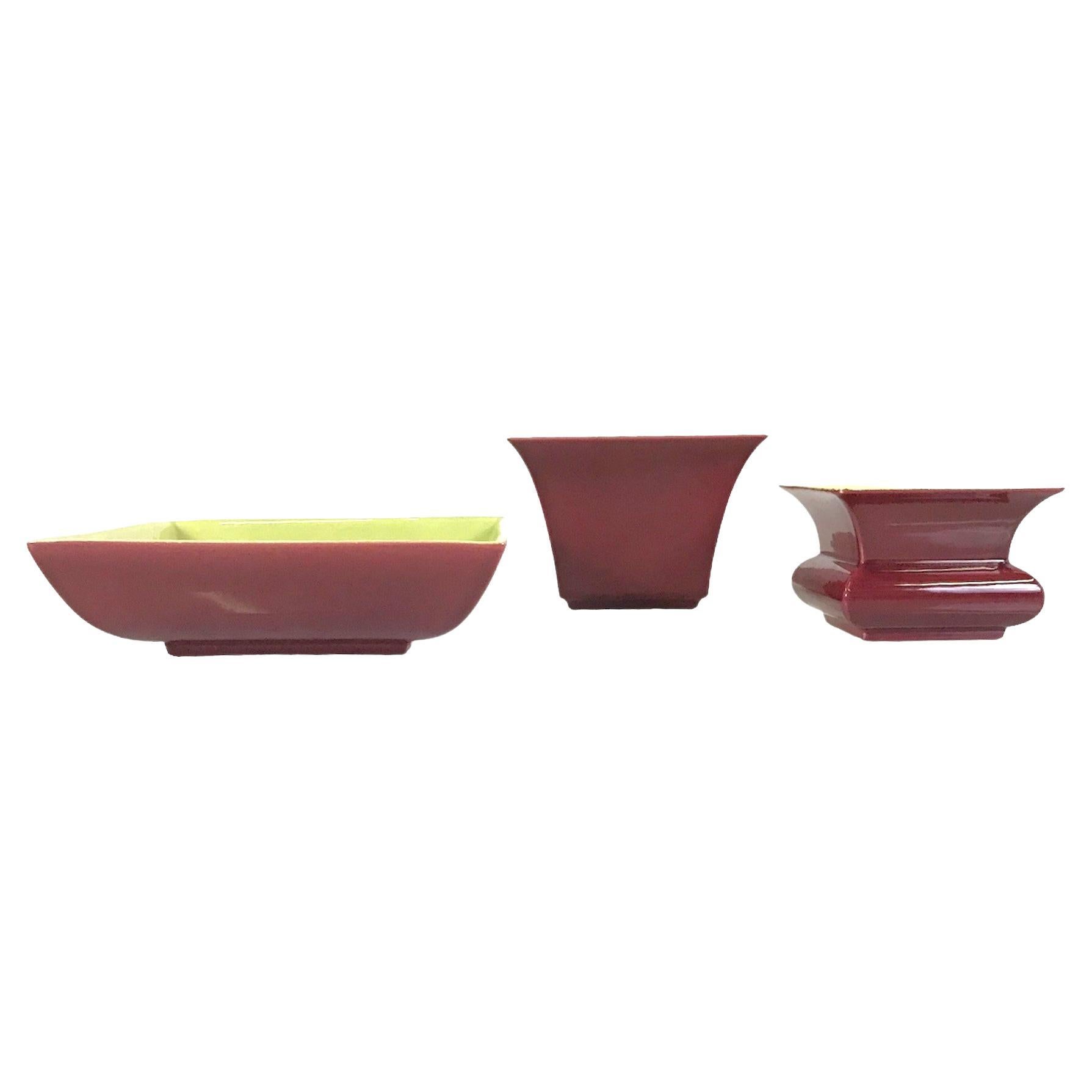 Asian inspired grouping of 3 rare ceramic vessels by Franciscan Ware division of Gladding-McBean Pottery. These 3 Mid-Century Modern pieces have a maroon glaze on the outside and either Mandarin Yellow, the two vases, or Lime Green glaze, bowl, on