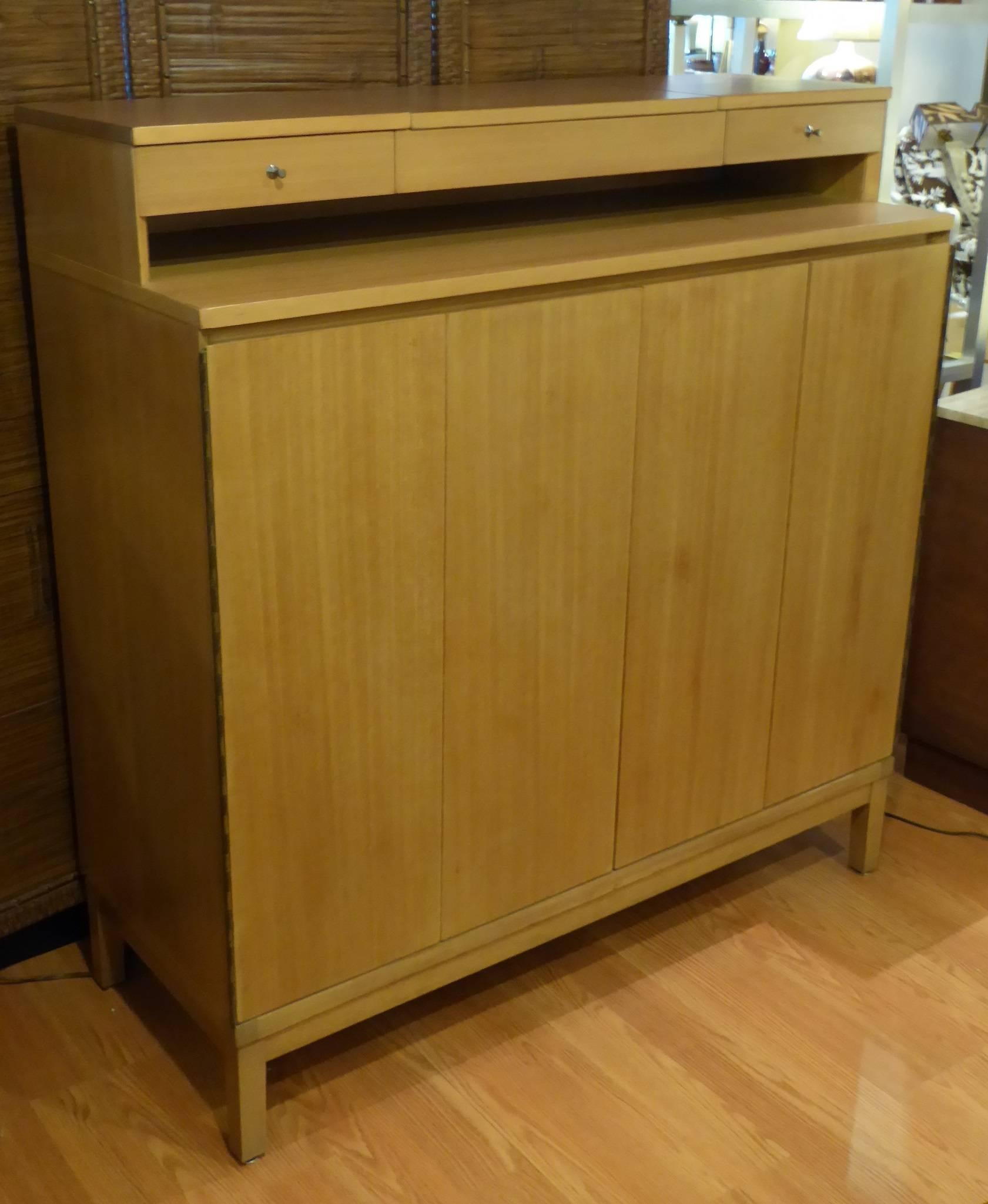 REDUCED FROM $4,500...In blond bleached mahogany, a Paul McCobb for Calvin Gentleman's chest dresser from the Irwin Series. With fitted interior behind bi-fold doors. The upper with two drawers and a lift up mirror. The fitted interior with shirt