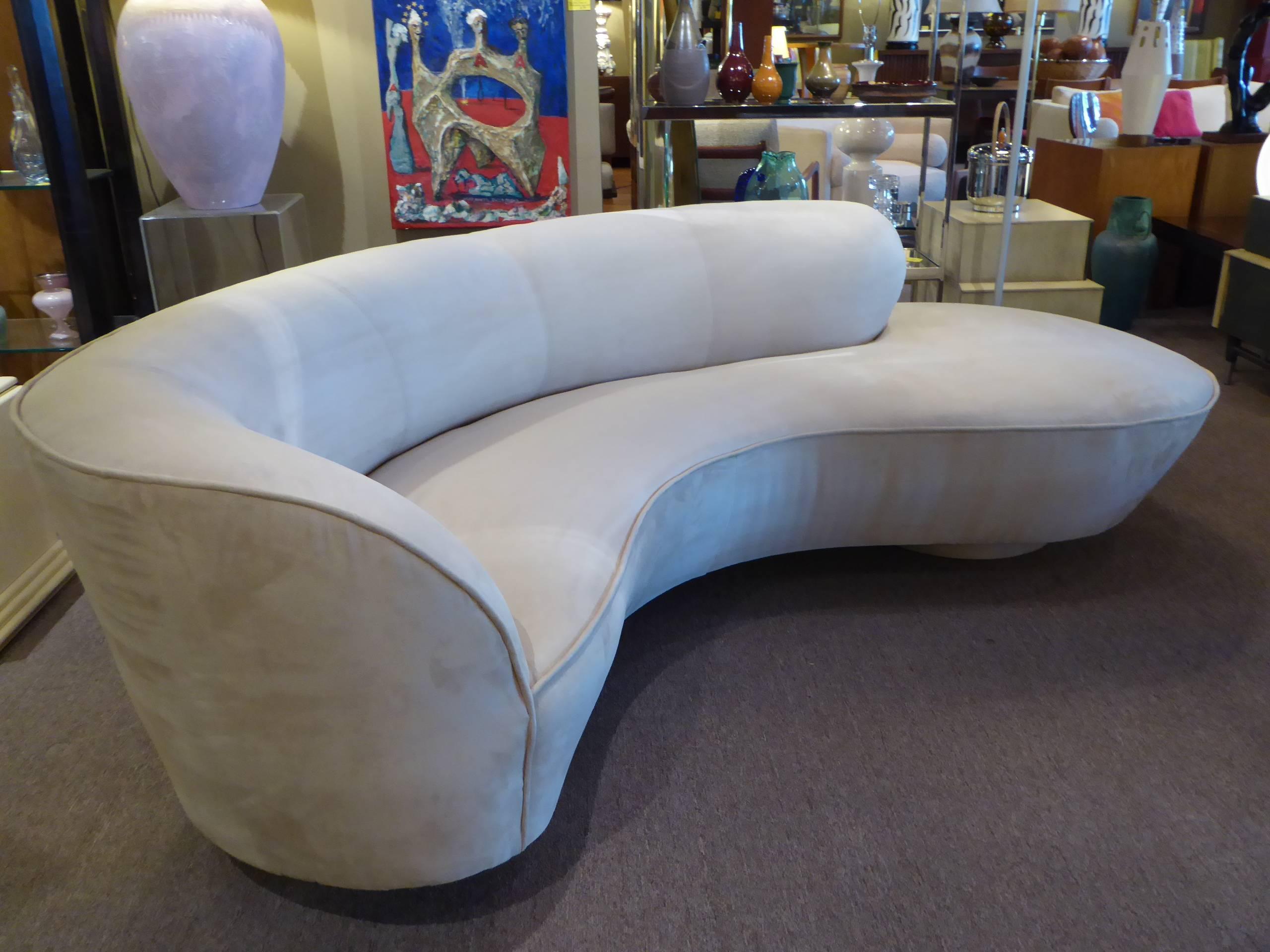 Sumptuous and iconic serpentine sofa by Vladimir Kagan for Directional. The sofa raised on two round, upholstered discs with extra support provided by a center Lucite slab. With Directional tag on underside. Newly upholstered in creamy ultrasuede,