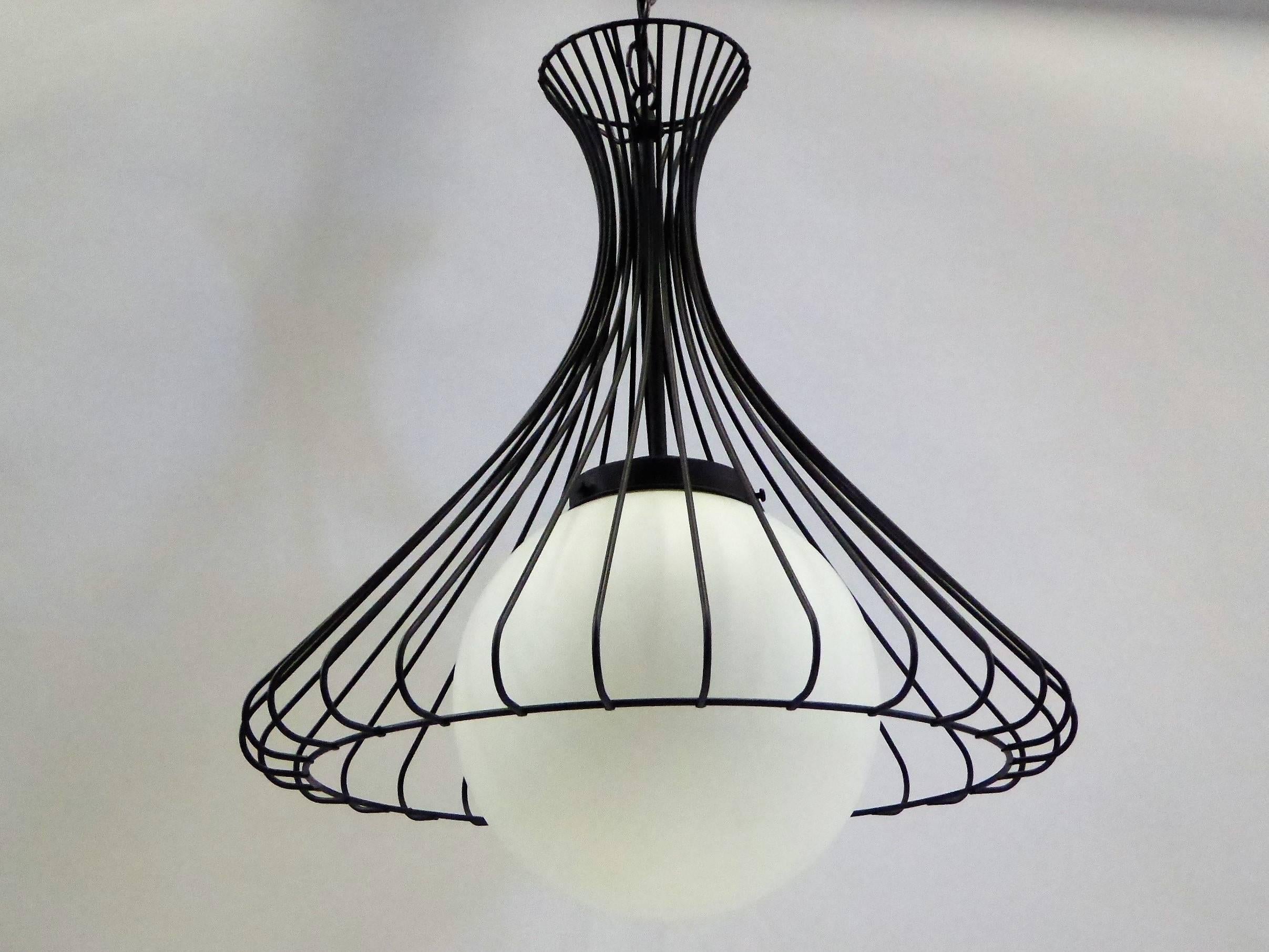 With a 1950s flair, this pendant chandelier has a steel wire bell shaped cage over a white satin glass globe. Rewired, restored and with new UL brass inner socket. Takes single medium base bulb, 75 watts max.
The fixture is 20 inches in diameter and