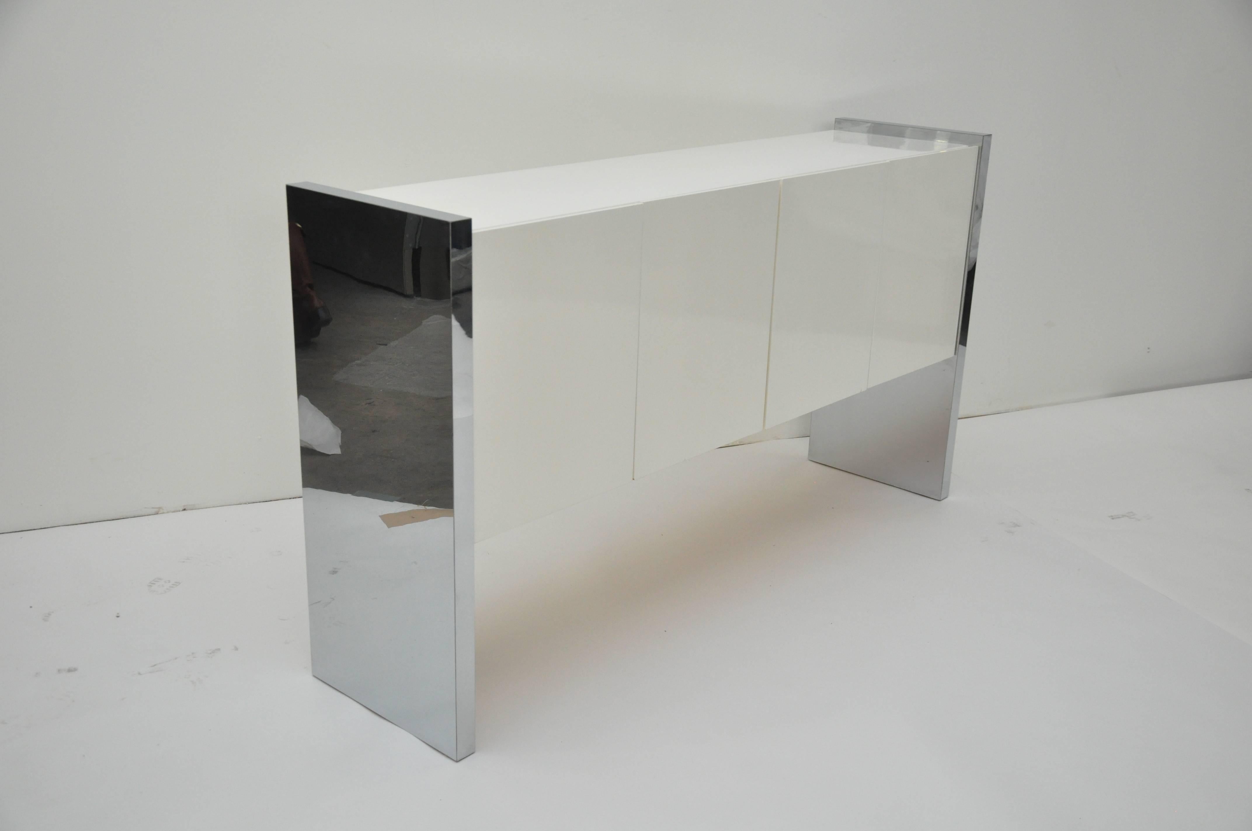 Design Institute of America Mid-Century credenza. Sides of credenza are chrome, four-door cabinet portion is laminate. Credenza has two slide out drawers and shelving.