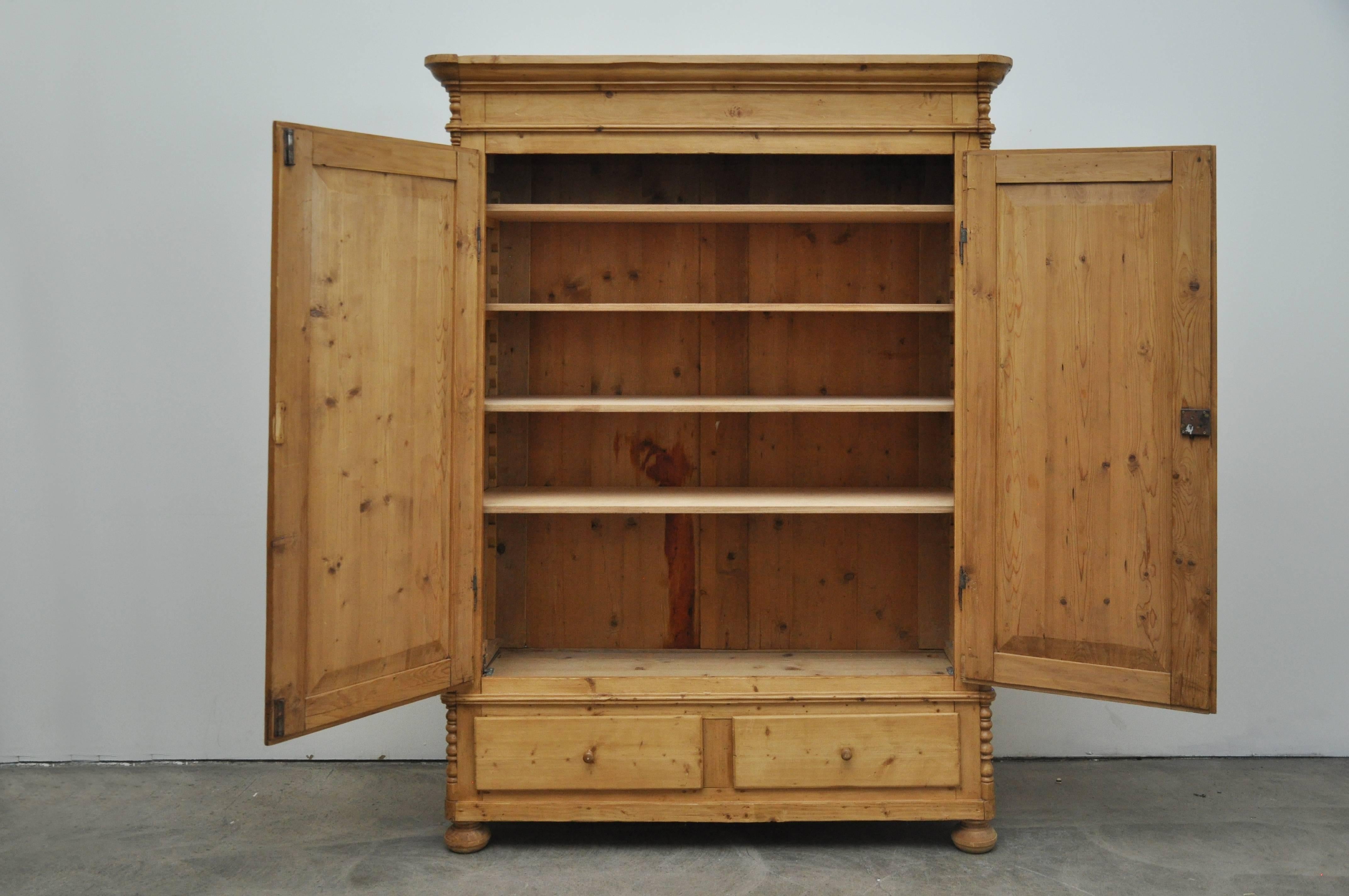 German pine cupboard, circa 1865. Cupboard has two doors and two drawers. Interior has five shelves. Bun feet and curved moldings.