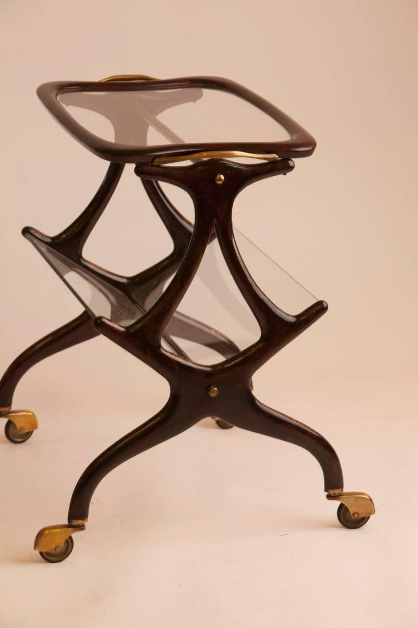 Wonderful and versatile rolling magazine rack/side table attributed to Italian designer Cesare Lacca. Table features glass tableau and magazine holder, lacquered wood and brass detail.